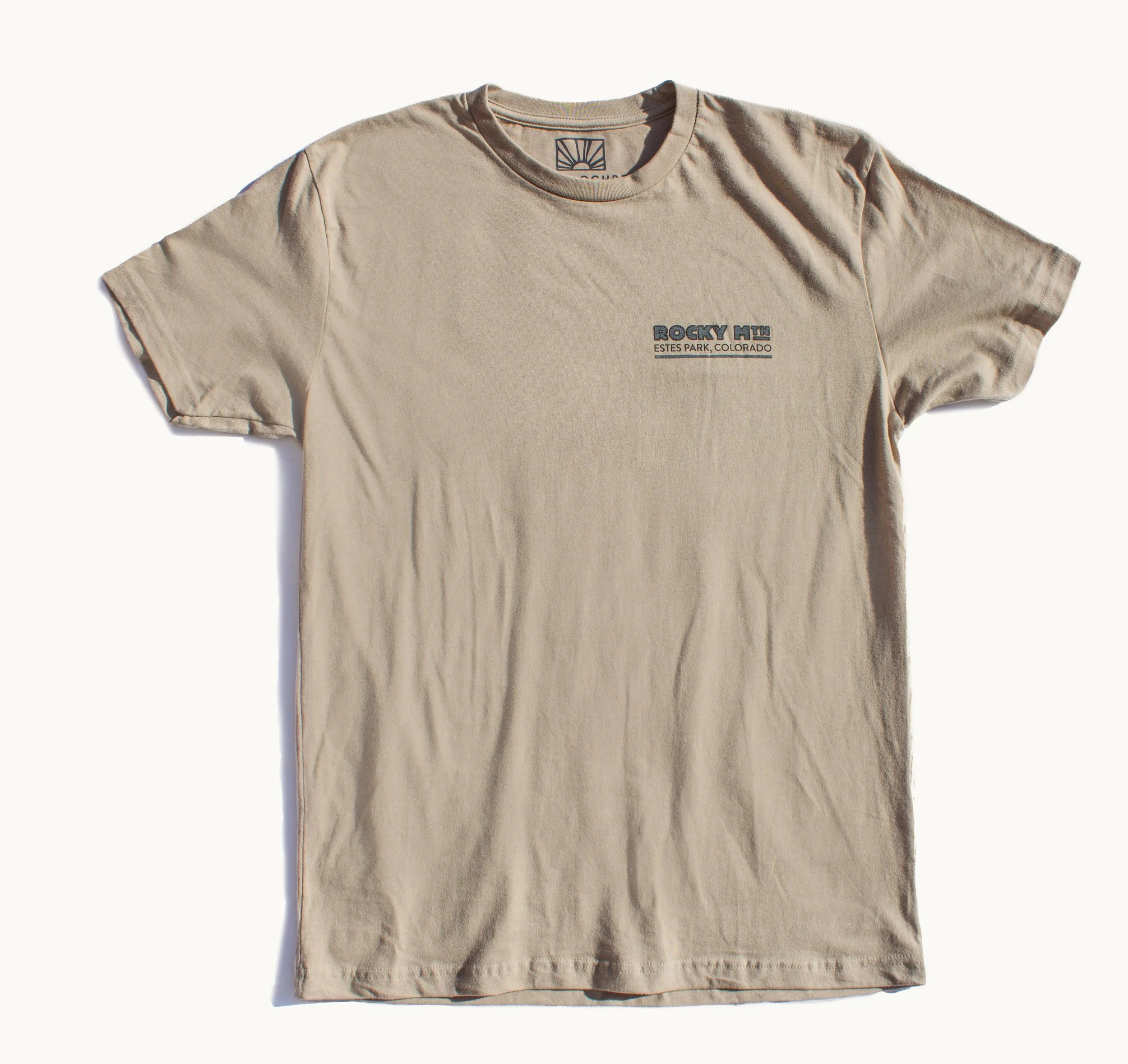 The front of a tan t-shirt showing the words Rocky Mtn Estes Park Colorado in the upper left breast area