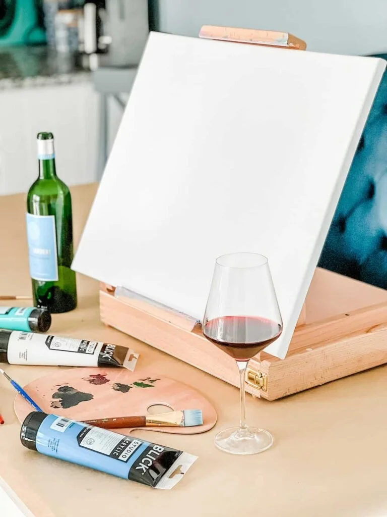 Blank-canvas-on-easel-with-painting-supplies-768x1024.jpg