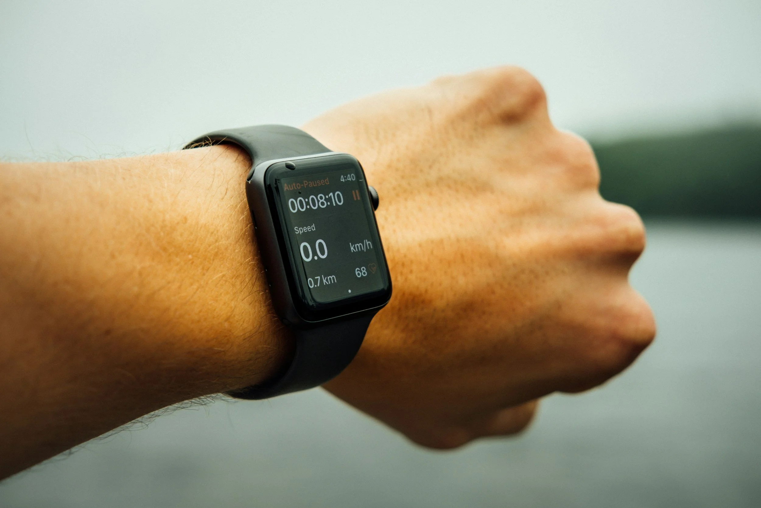 Close-up of a person's wrist wearing a black smartwatch displaying a timer, speed, and distance during a workout.