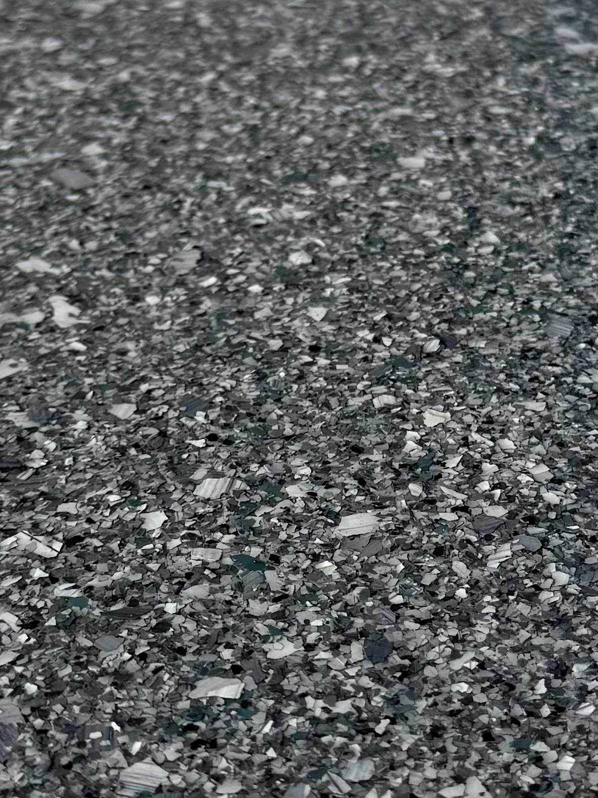 Close-up of a textured surface composed of numerous small, irregularly shaped fragments of gray and black material.