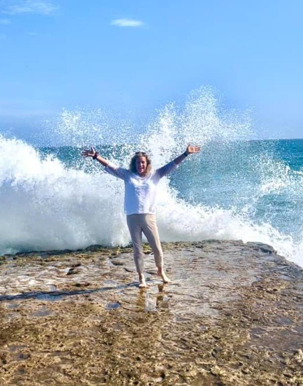 Gabrielle England on the beach in Santa Cruz, California with waves crashing behind her.