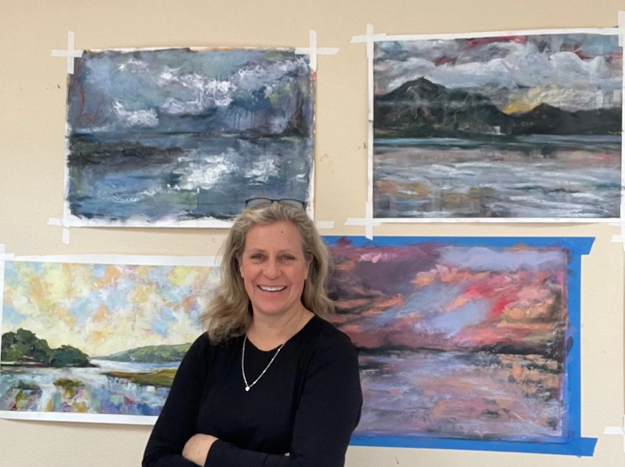 Gabrielle England standing in front of her landscape paintings in her studio.