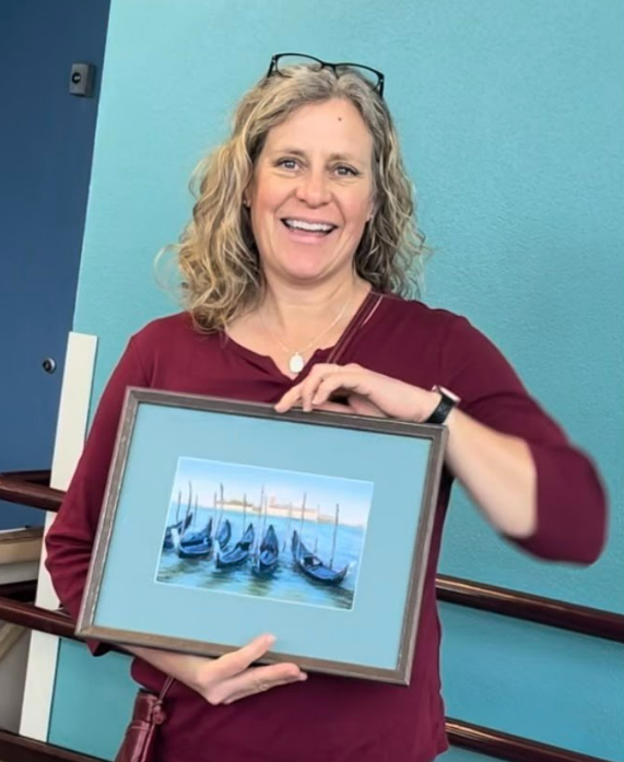 Artist Gabrielle England holding a framed painting.