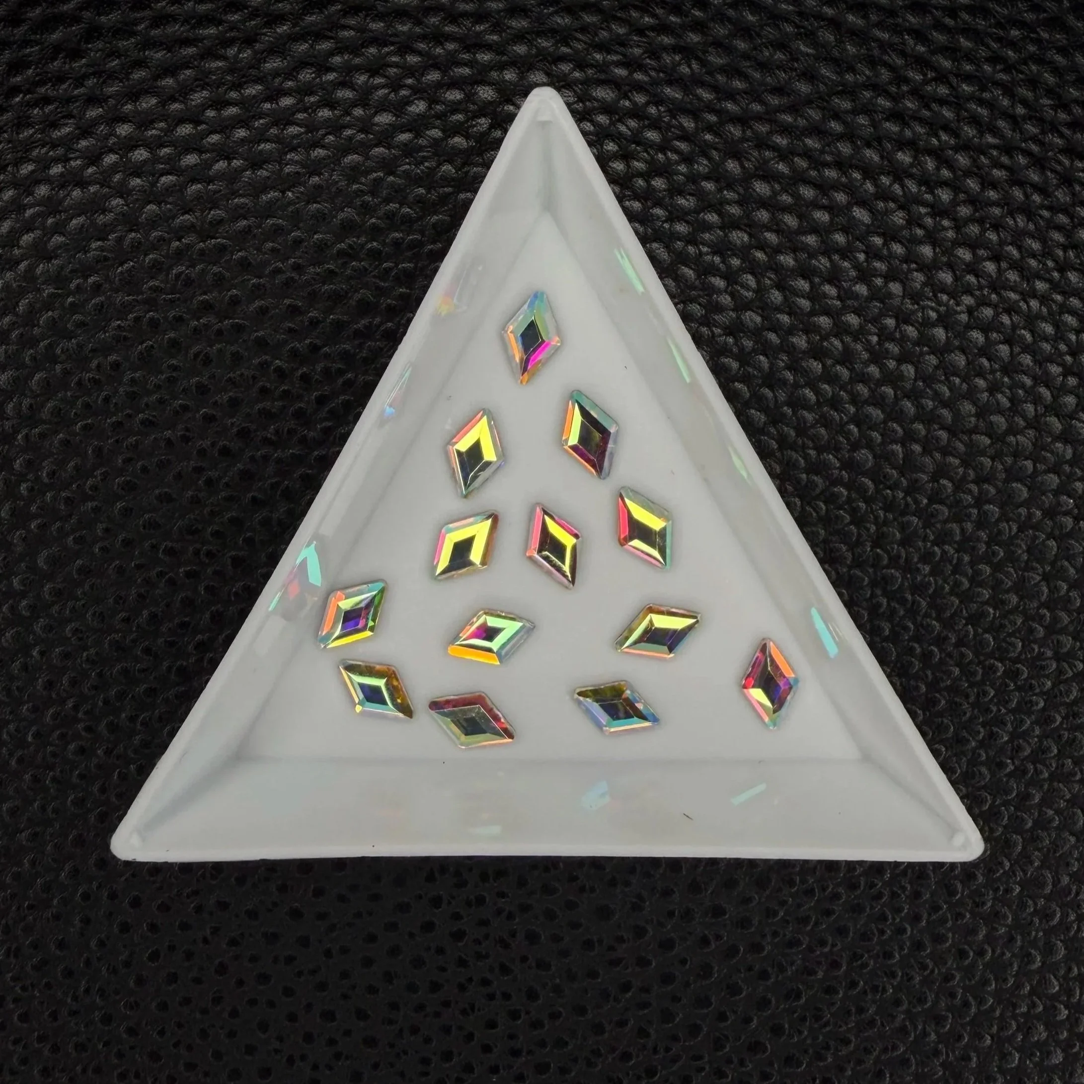 Rhombus-shaped flatback rhinestones arranged in a triangular dish for display.