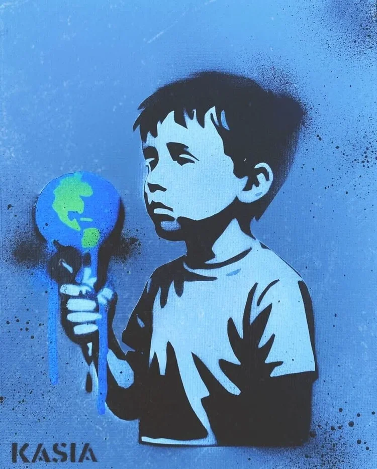 Street art graffiti of a young boy with short dark hair, holding a small globe on a stick, painted in shades of blue and black with the signature 'KASIA' in the bottom left corner.