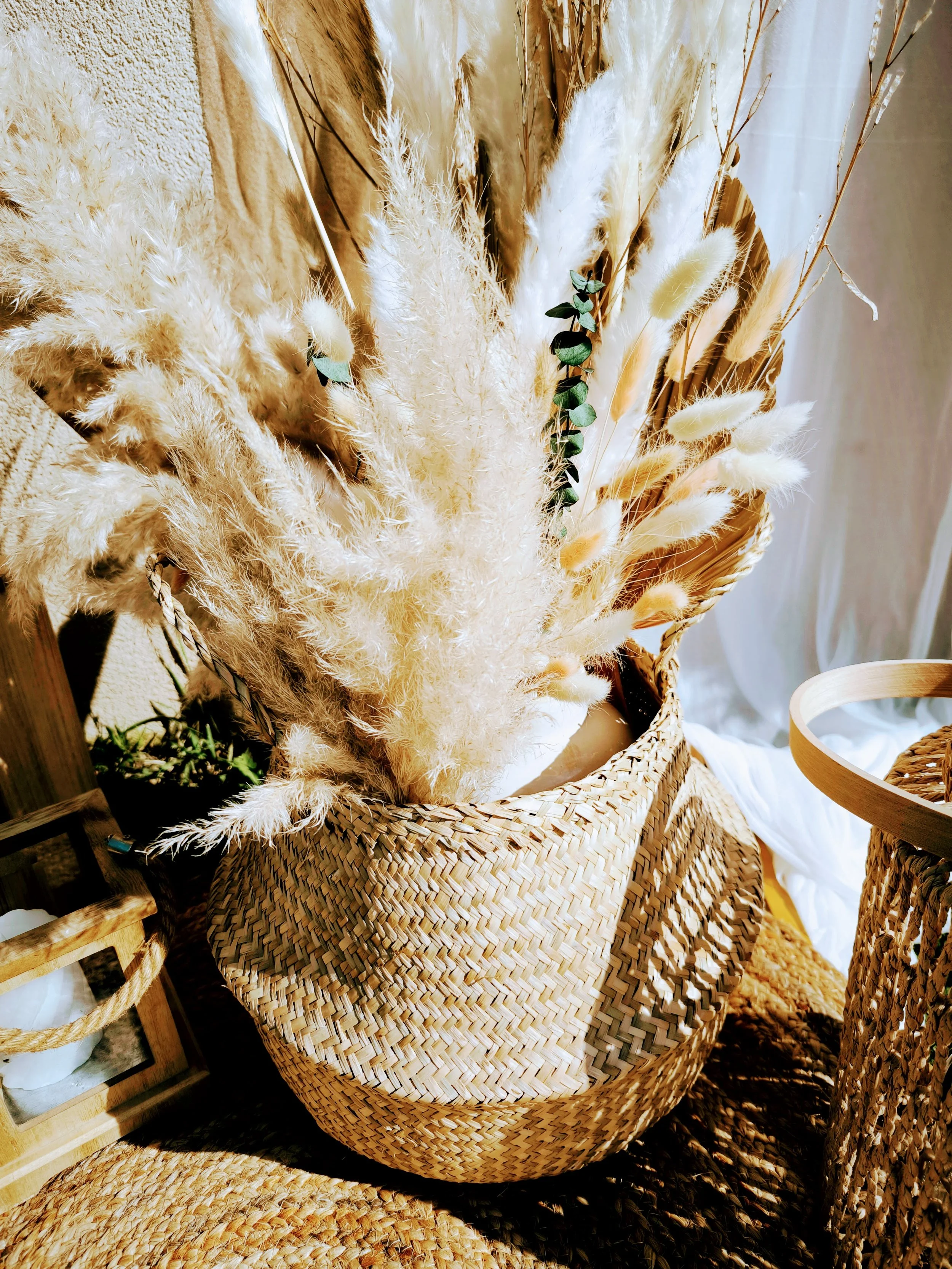 Panier en rotin rempli de fleurs séchées couleurs crème et beige dans un décor naturel.