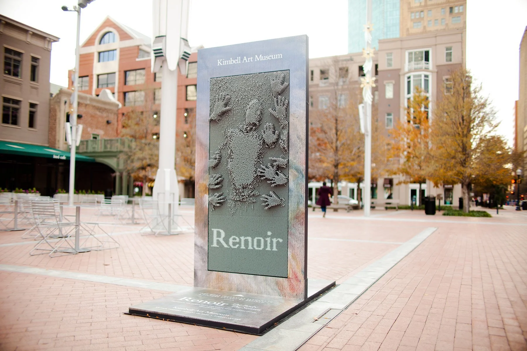 Public outdoor art installation at Kimbell Art Museum showcasing a textured portrait with the word 'Renoir' below it, set on a large metallic stand.