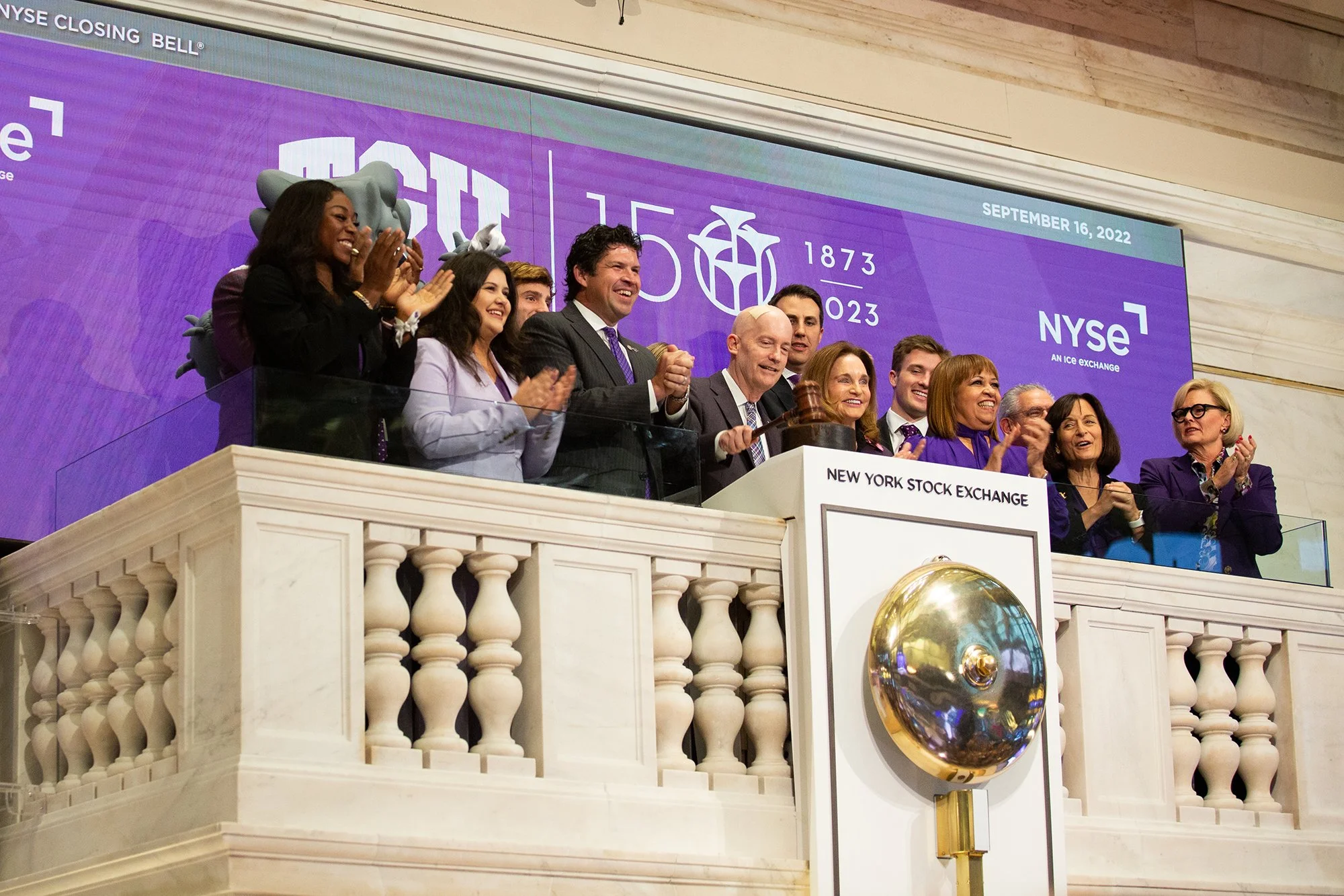 Group of people celebrating during a bell-ringing ceremony on a balcony at the New York Stock Exchange.