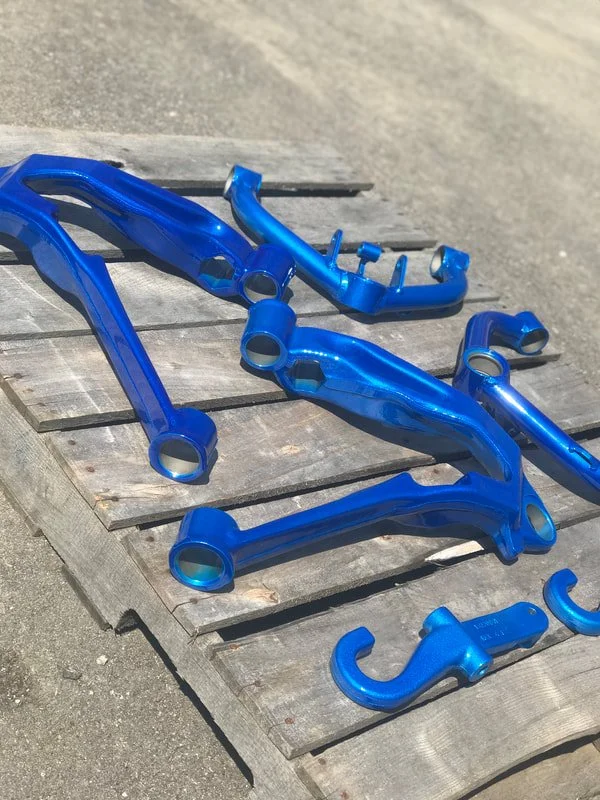 Blue painted bicycle stanchions or suspension forks lying on a wooden pallet outdoors.