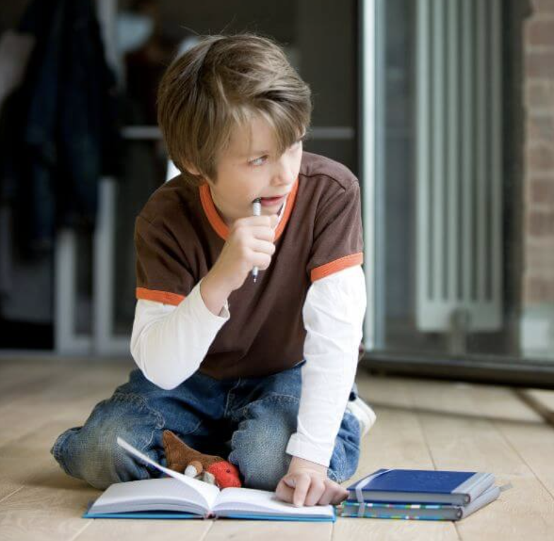 Niño arrodillado en el suelo con un libro abierto, en una escena de inquietud y dificultad para mantener el foco.