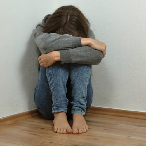 Niño sentado en el suelo con los brazos rodeando las piernas, imagen que representa irritabilidad, impulsividad y conflictos de convivencia.