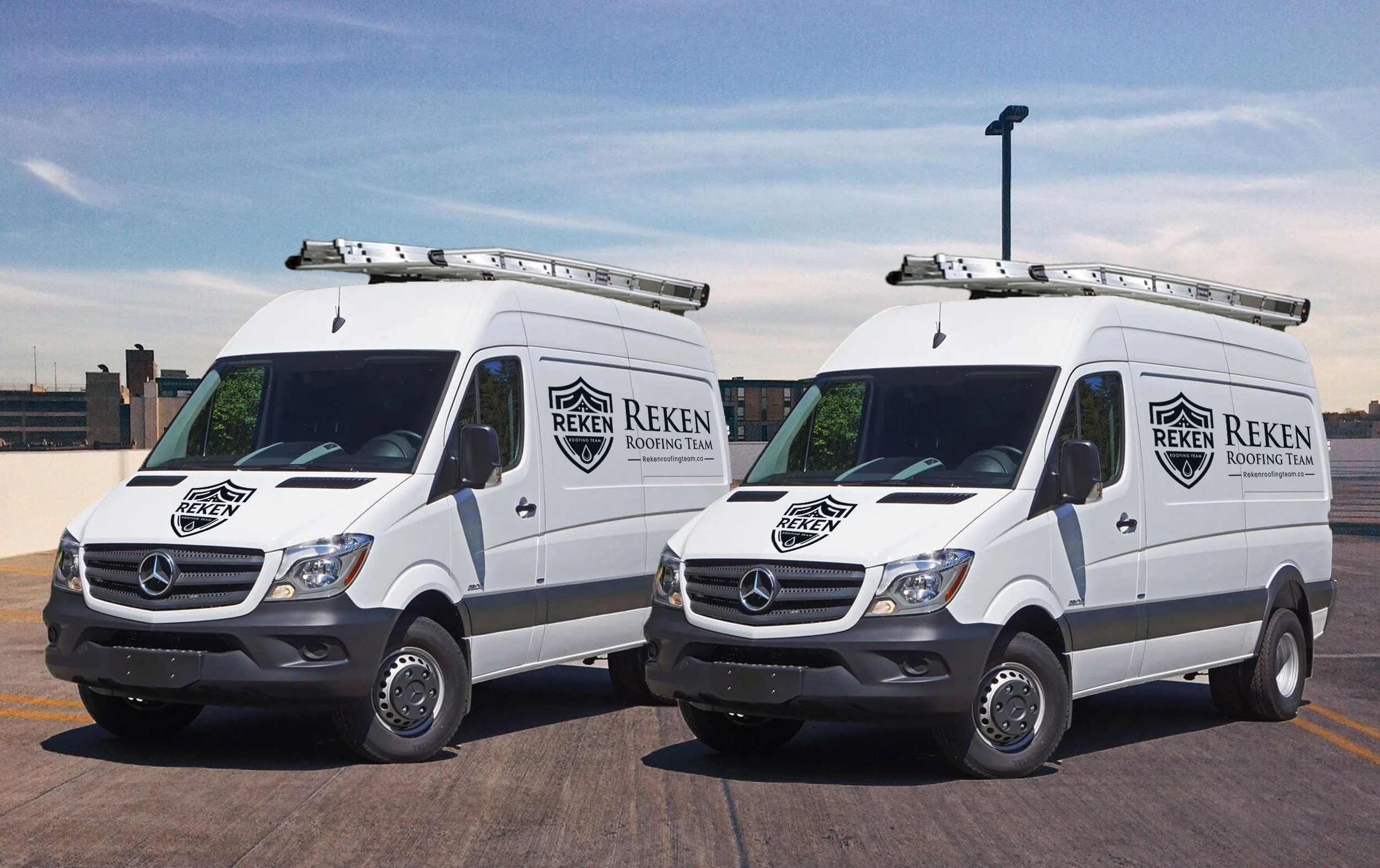 Two white service vans with ladder racks on the roof, parked side by side on a rooftop parking lot. The vans have "REKEN ROOFING TEAM" logos on the sides and front.