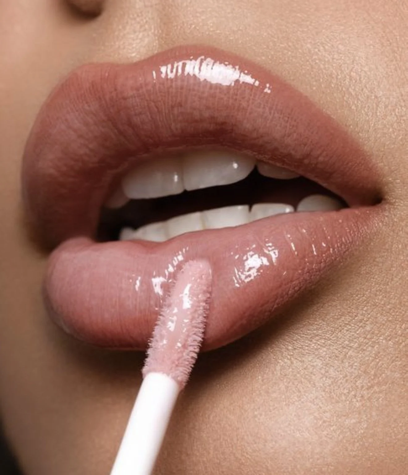 Close-up of lips with gloss applying lip gloss using a lip applicator.