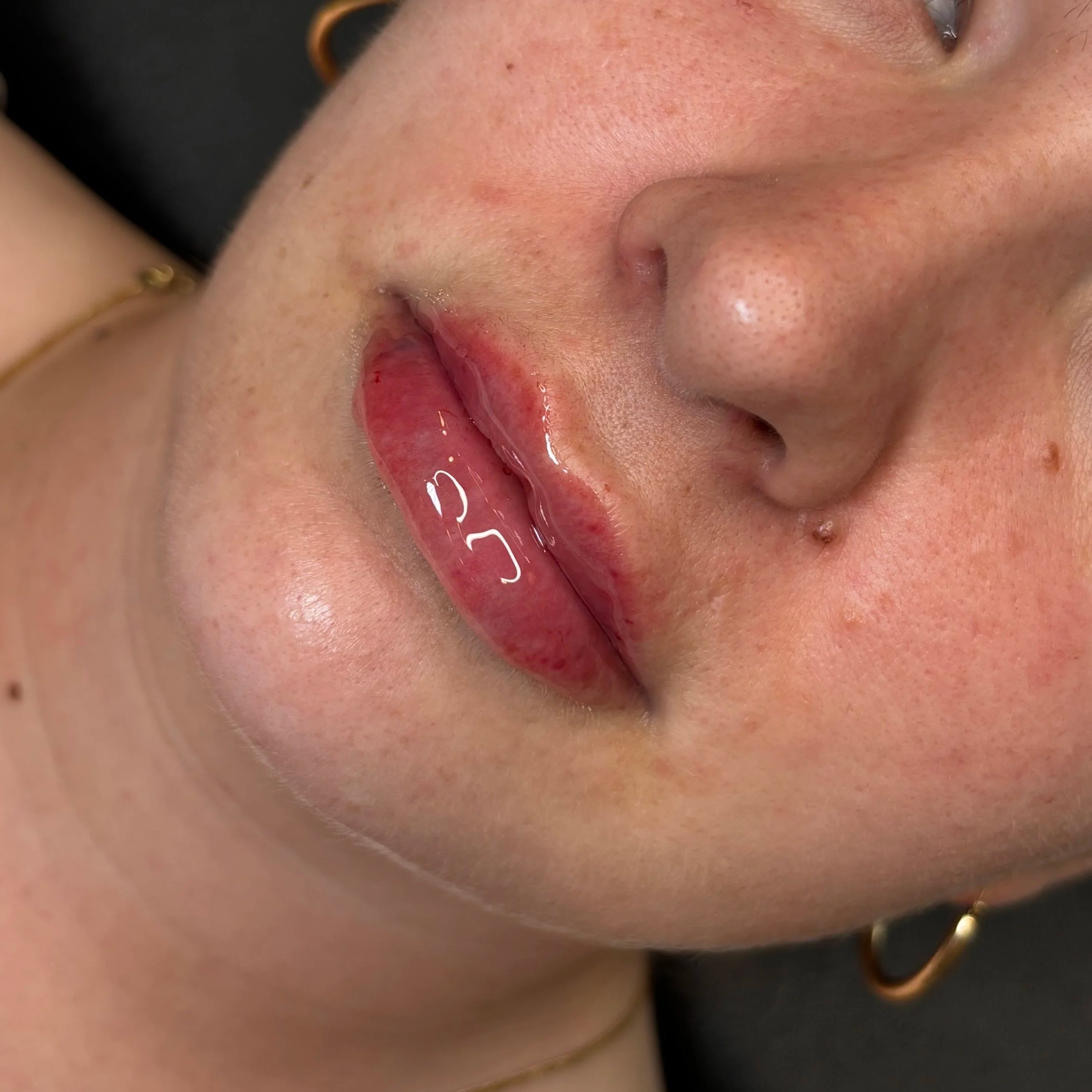 Close-up of lips with gloss applying lip gloss using a lip applicator.