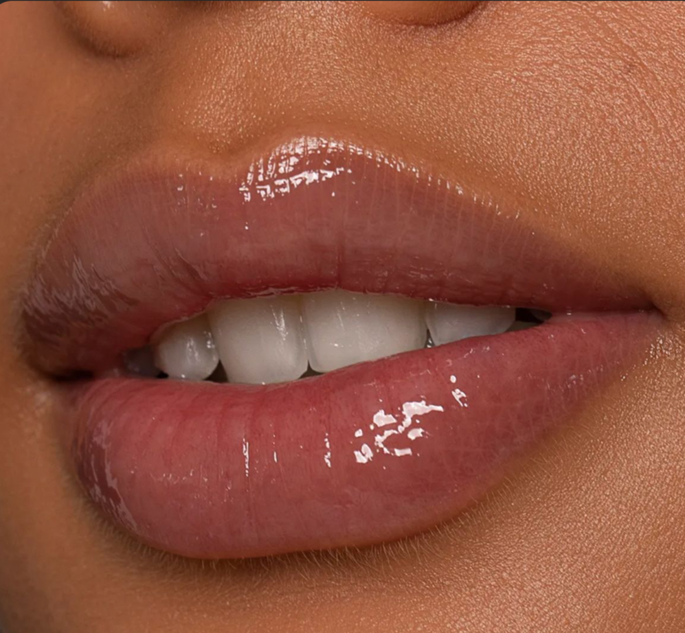 Close-up of lips with glossy pink lipstick, a few teeth visible, and smooth skin.