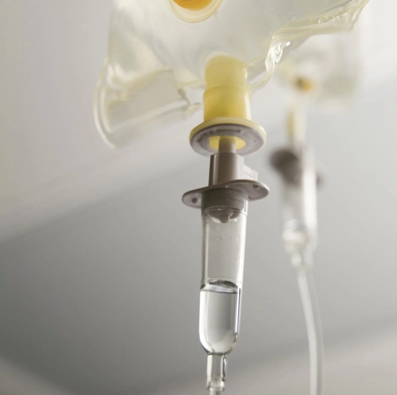 Close-up of an IV drip with a tube filled with clear liquid hanging from a medical pole.