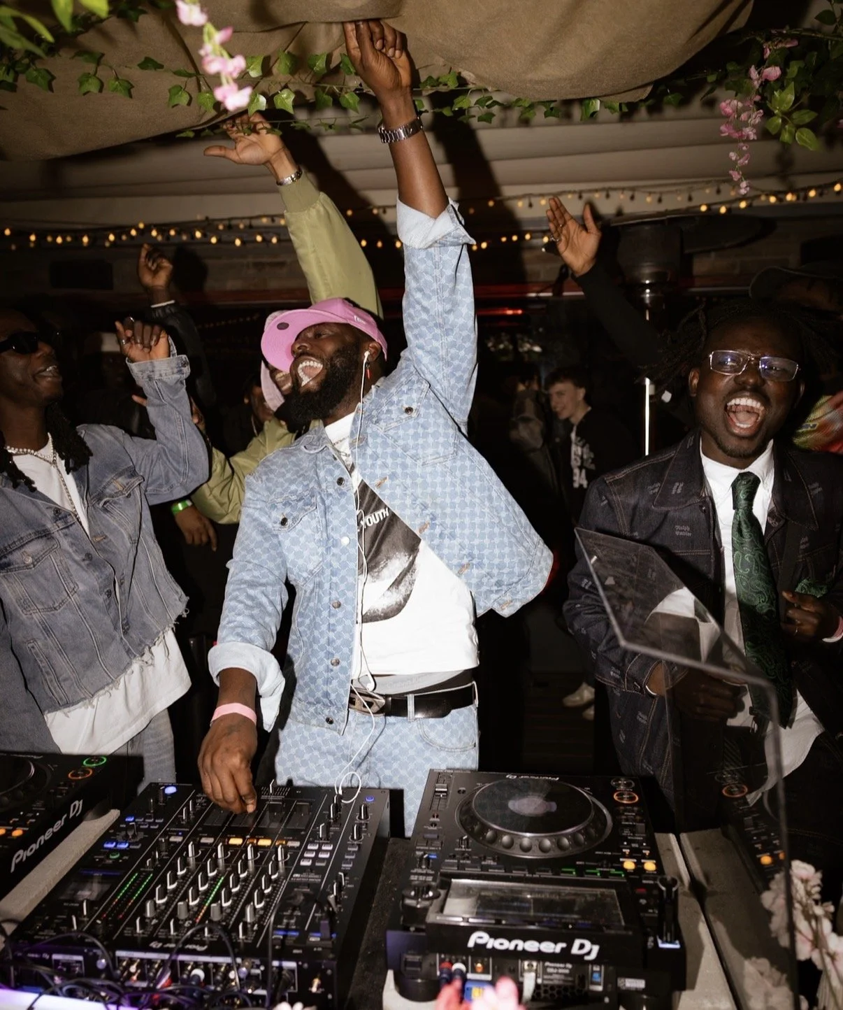 People dancing and enjoying themselves at a lively party with DJ equipment in the foreground.