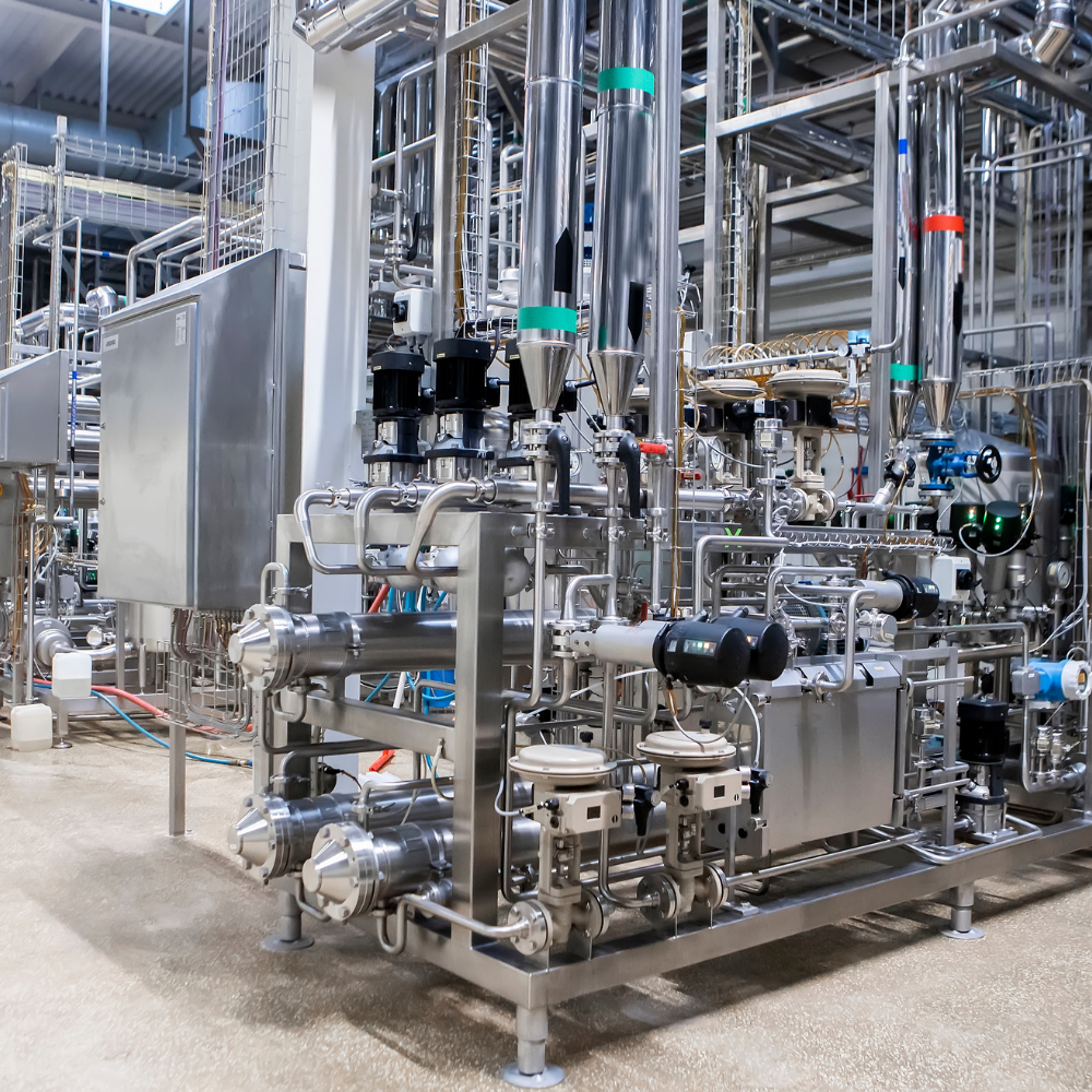 Industrial processing equipment with stainless steel pipes and machinery in a clean factory setting.