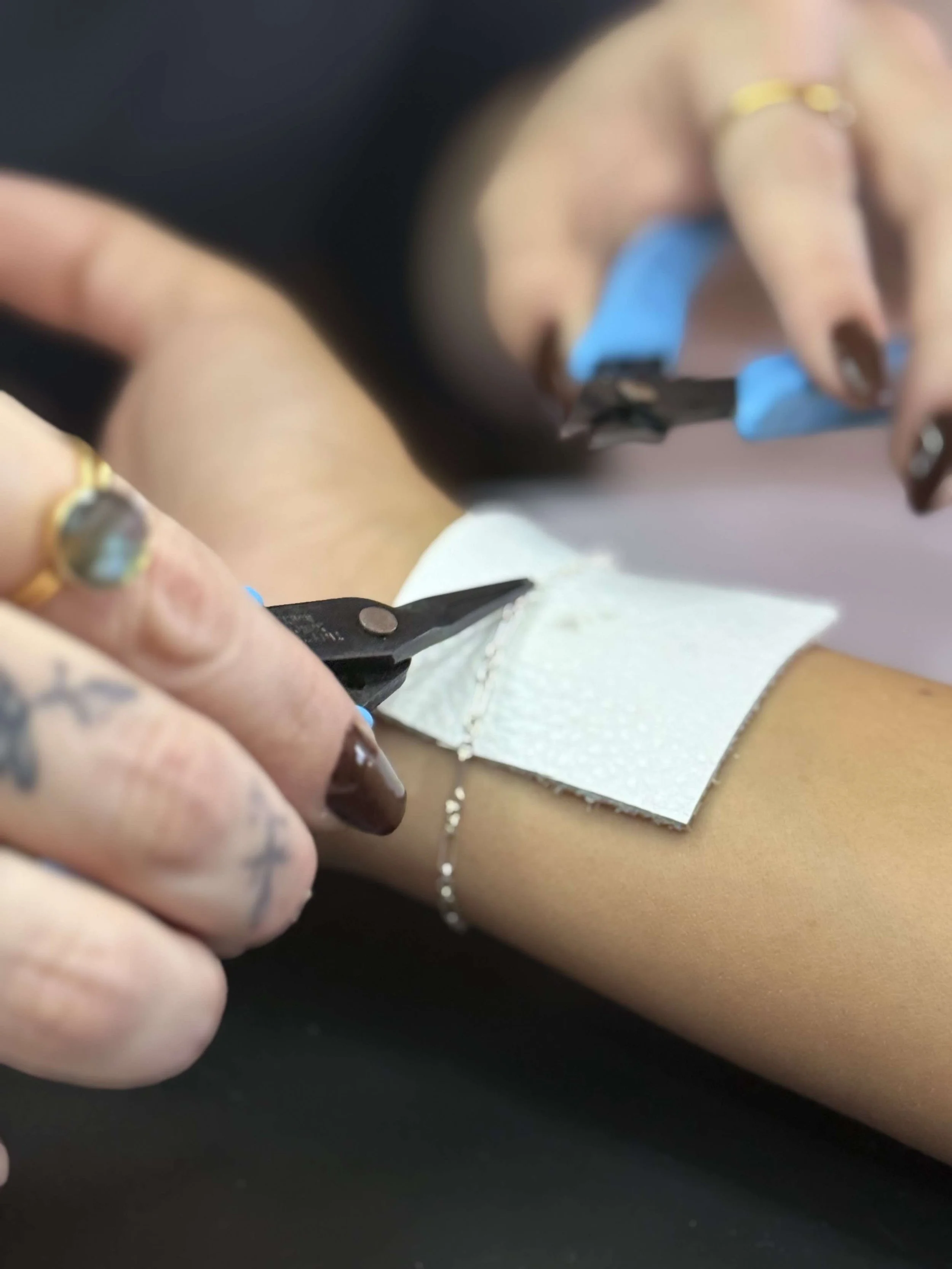Close-up of a person's arm with a medical bandage, a needle, and a strip of gauze, as a healthcare professional draws blood.