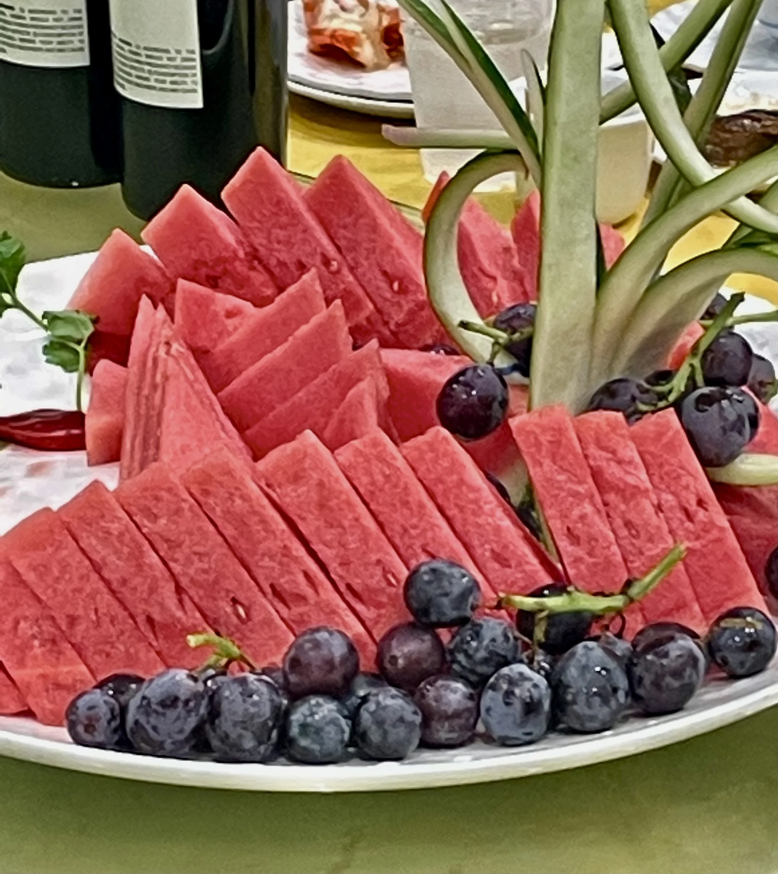 Sliced watermelon, pineapple, and blueberries on a white platter.