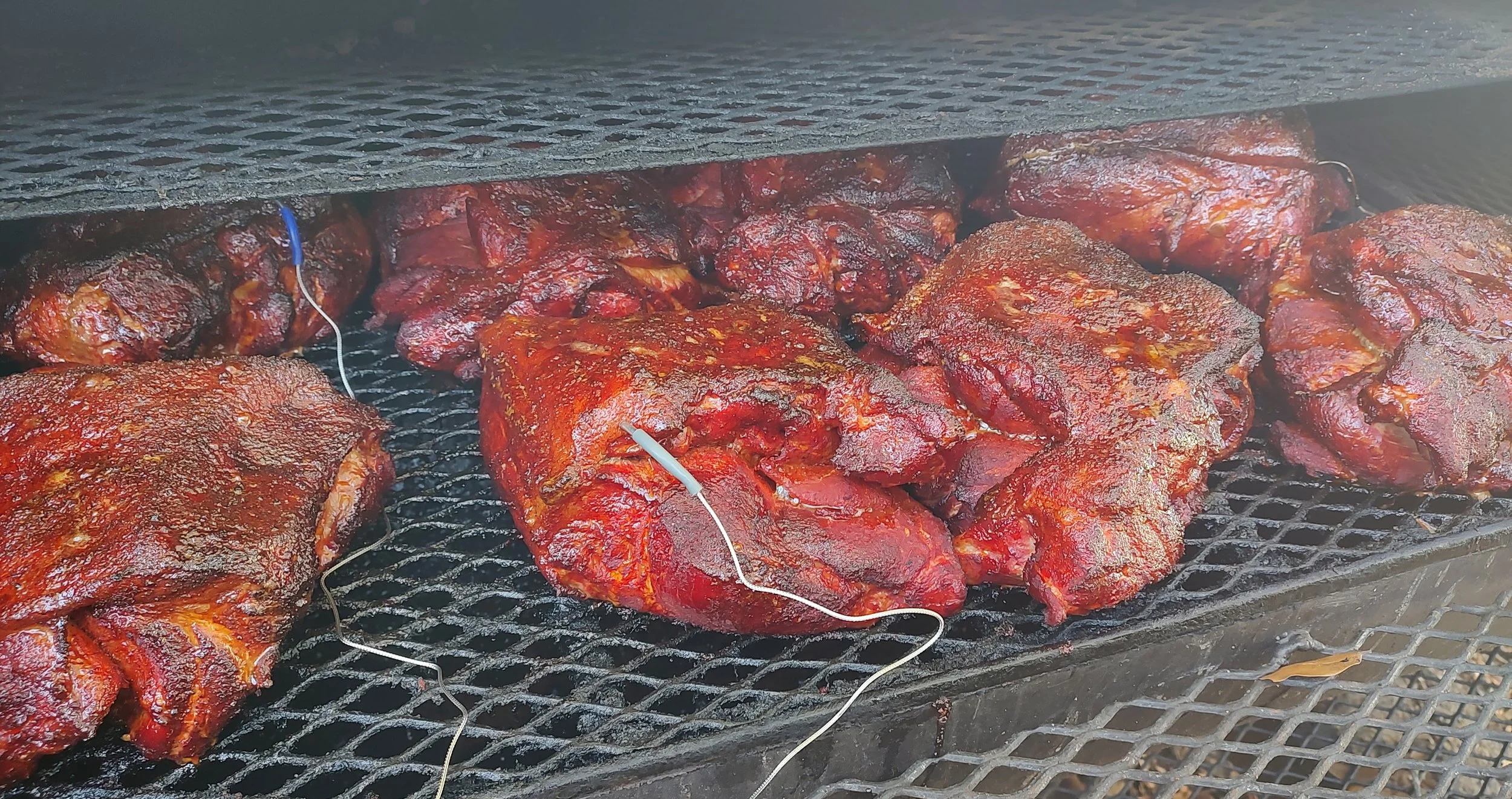 Slow-smoked barbecue pork cooking on a smoker for catered events by Smokin’ Crow’s BBQ in Southwest Florida.