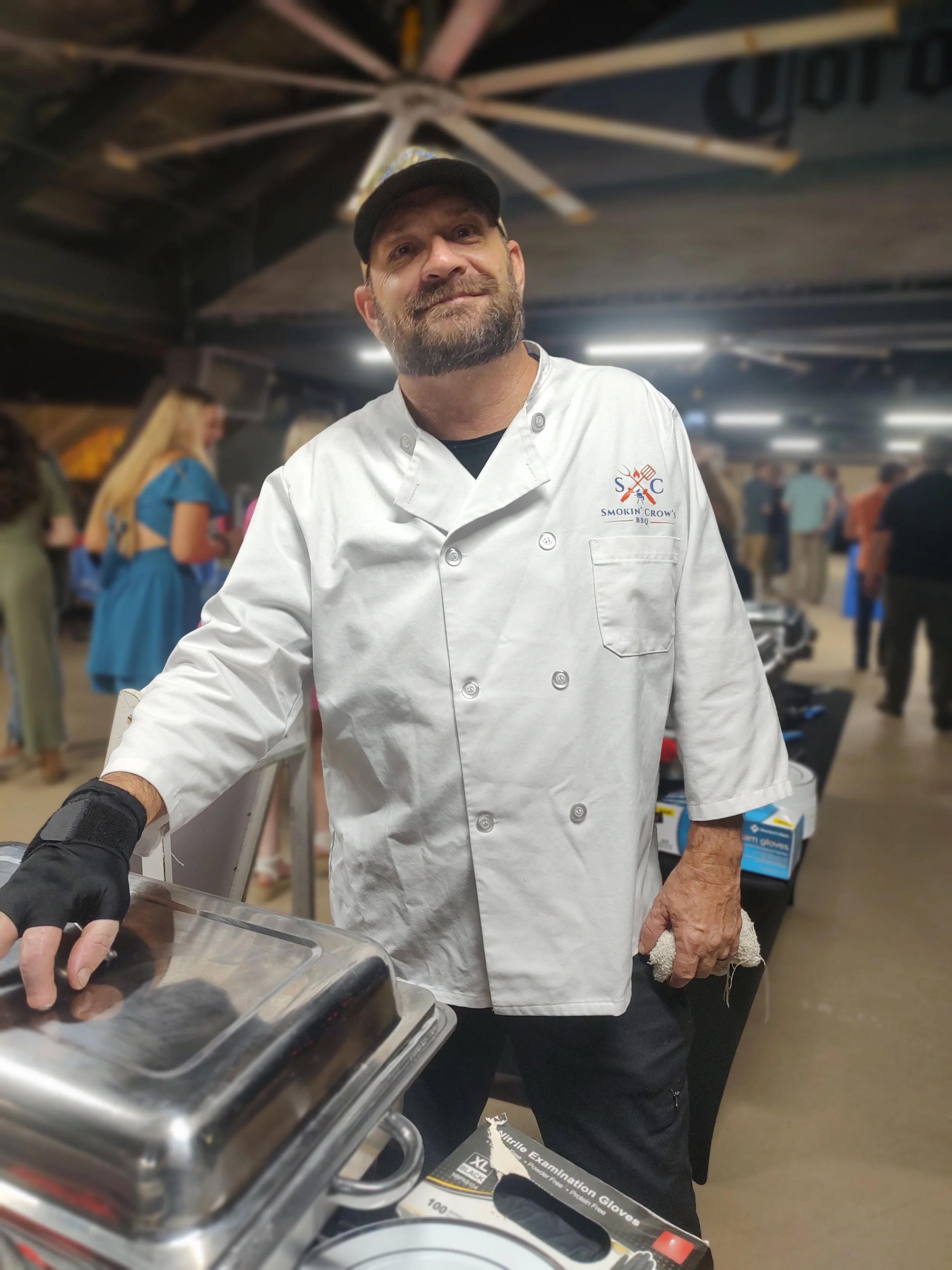 Michael Crow, pitmaster and owner of Smokin’ Crow’s BBQ, overseeing barbecue catering at an indoor event.