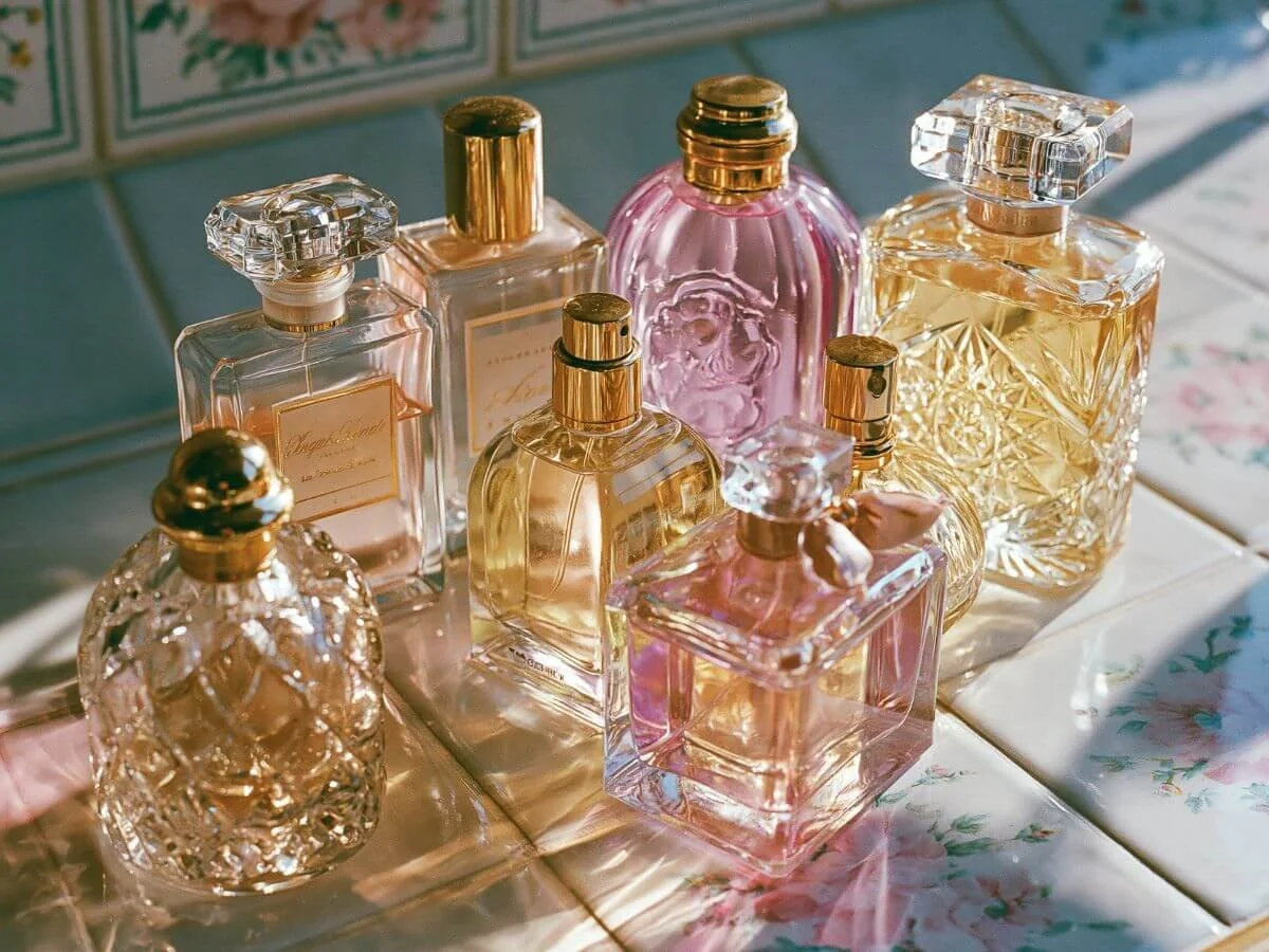 Vintage-inspired perfume bottles in soft pink and gold on a floral vanity table.