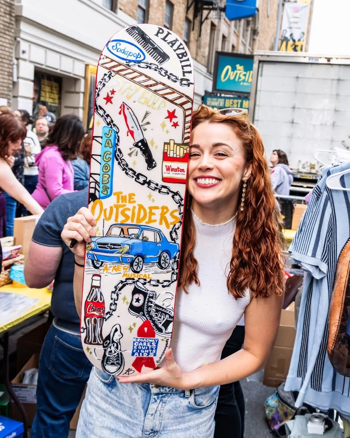 Emma Pittman holding a custom skateboard at BCEFA flea market