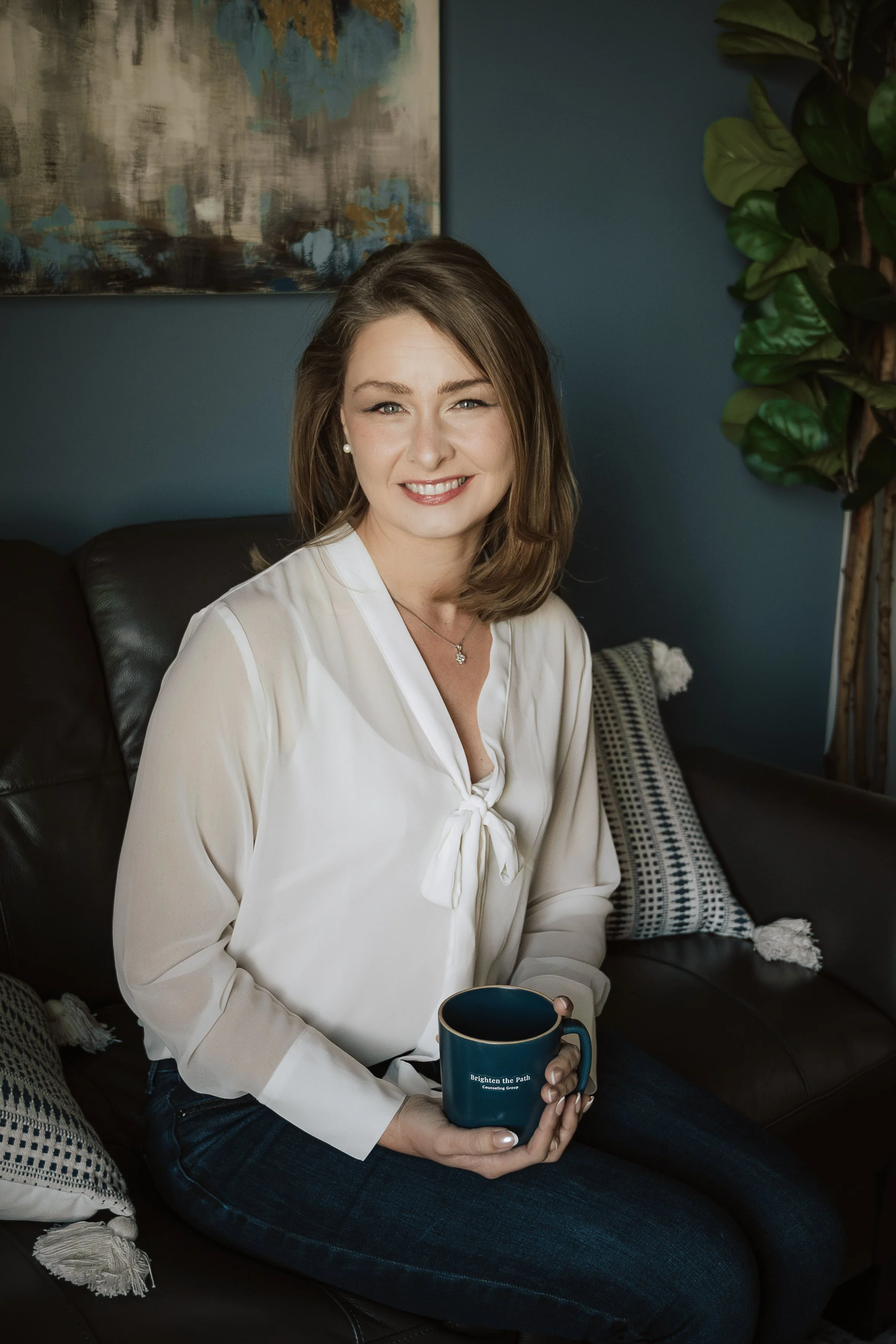 Headshot featuring therapist Rachel Clayton, sitting on a couch, holding a coffee mug