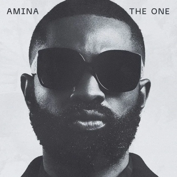 Black and white photo of a man with a beard wearing sunglasses, with the words 'AMINA THE ONE' above him.
