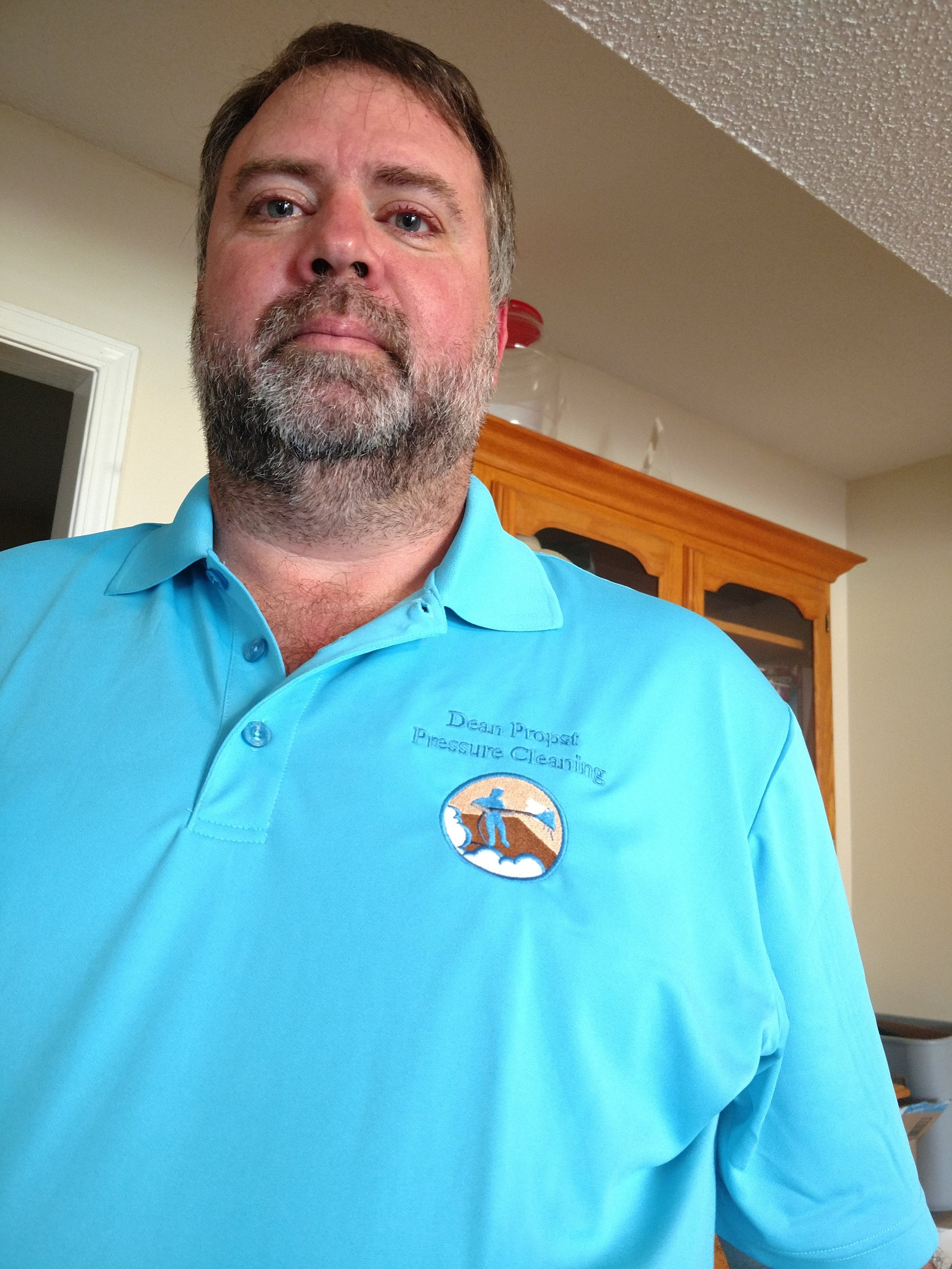 Close-up of the owner wearing a light blue polo shirt with a company logo.