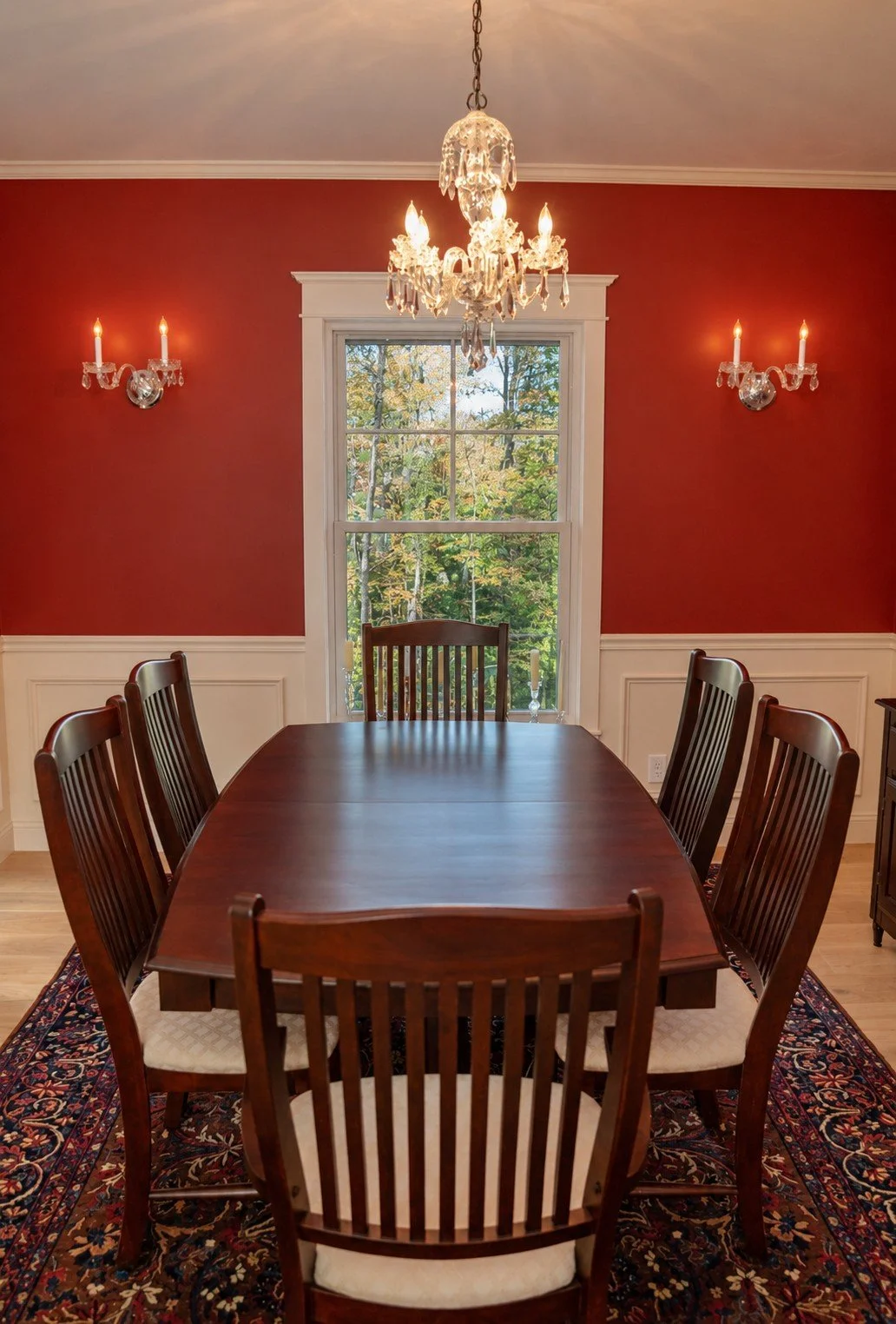 Formal dining room with red walls, wainscoting, and a crystal chandelier