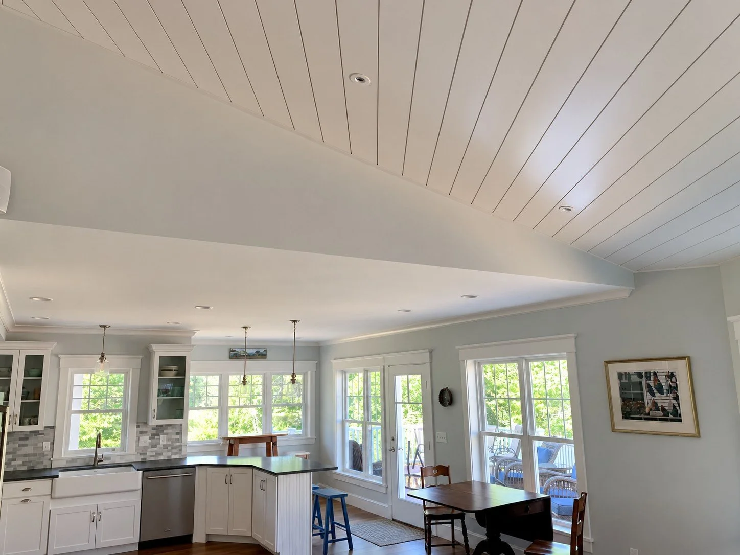 Open kitchen and dining room under a white paneled ceiling with French doors to the porch