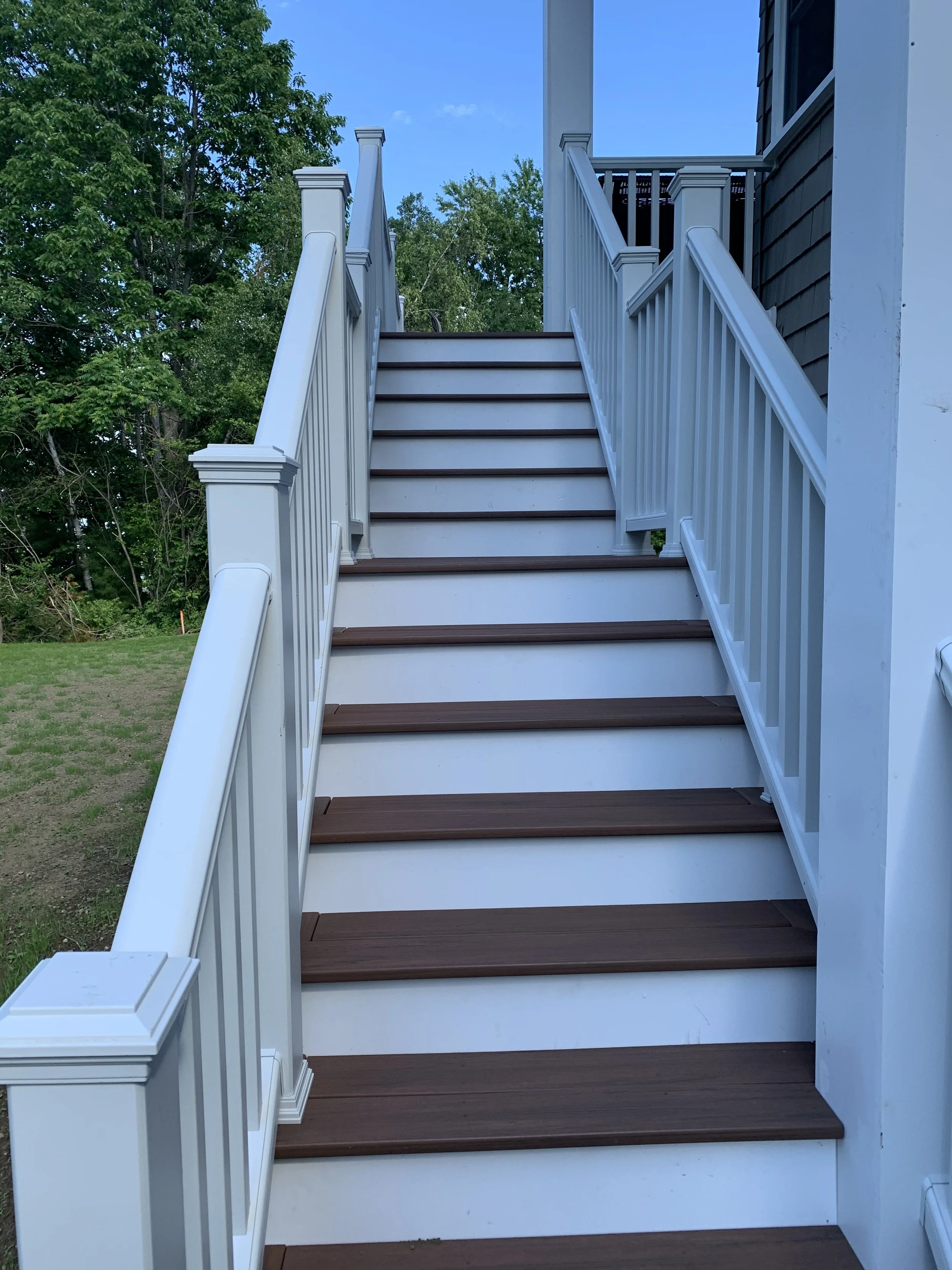 Exterior wooden stairs with white railings and painted risers