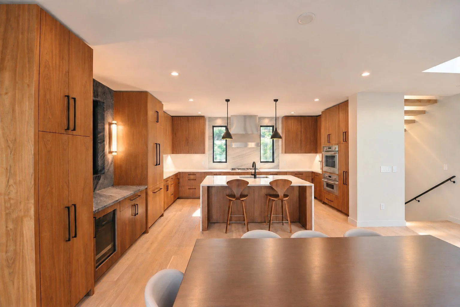Kitchen with walnut cabinets, a large island with stools, and light oak floors