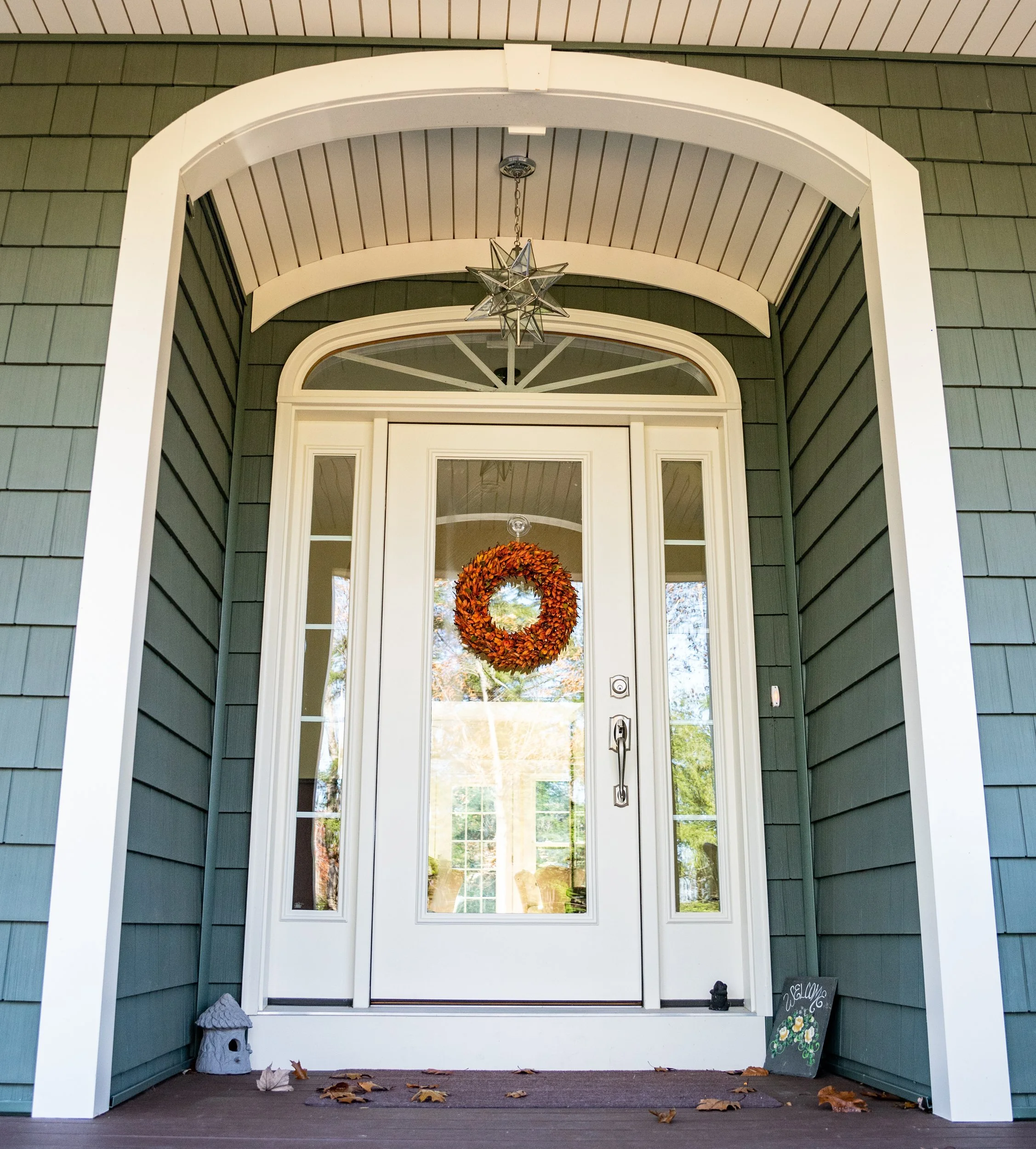 Arched covered entry with a full-glass front door, sidelights, and transom