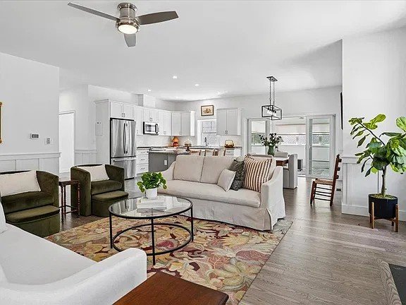 Open concept living room and kitchen with gray plank flooring and a floral area rug