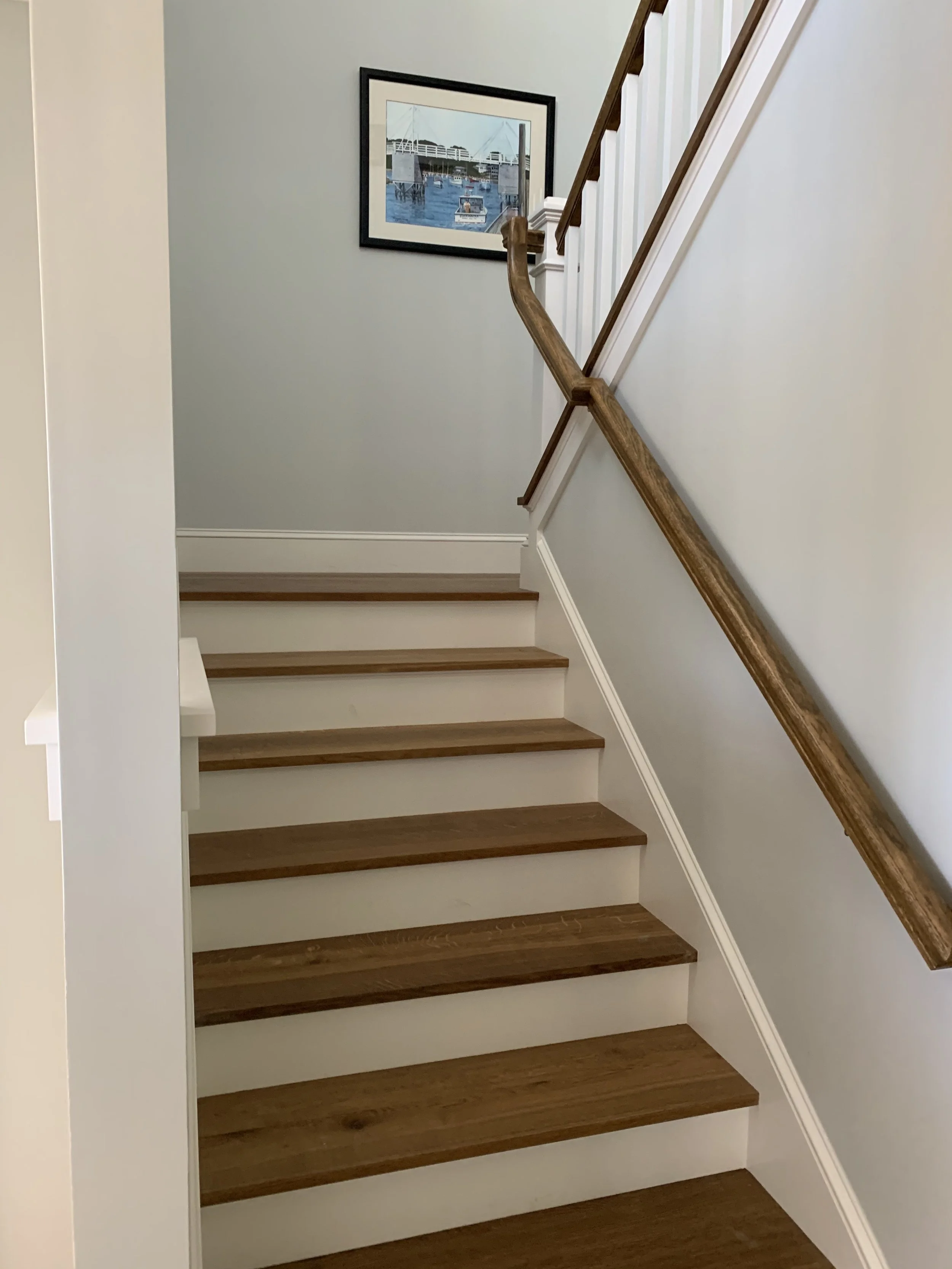Interior staircase with wood treads, white risers, and a wood handrail