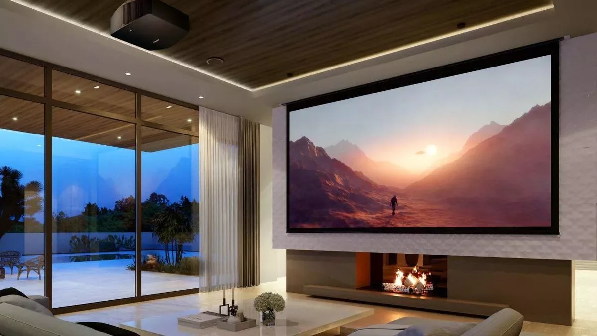 Modern living room with a large flat-screen dvLED TV displaying a scenic mountain landscape at sunset, with a fireplace below, and large windows showing an outdoor patio and garden at dusk.