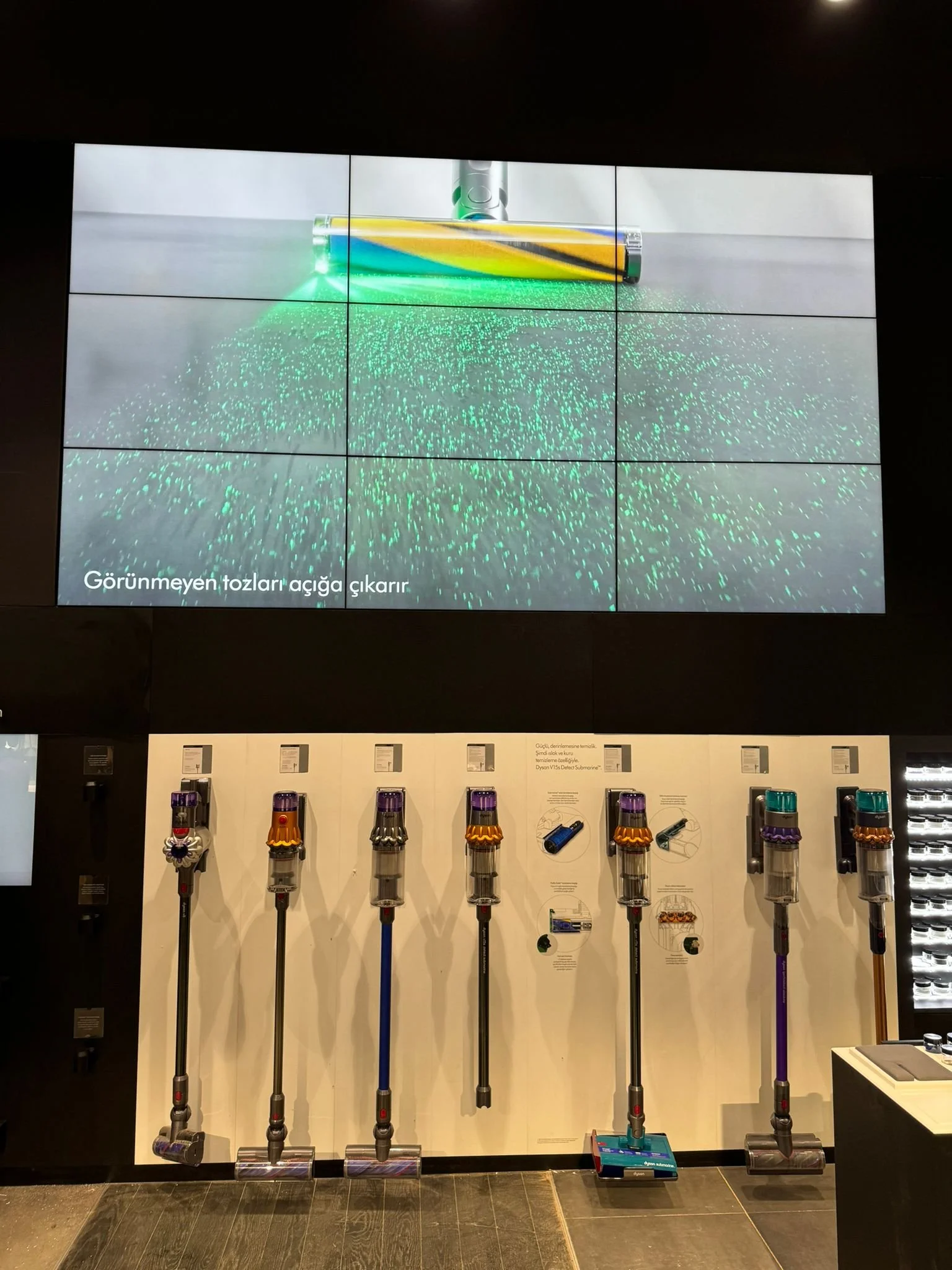Large LCD video wall displaying of various Dyson vacuum models with a large screen showing a demonstration of a vacuum cleaning at the top.
