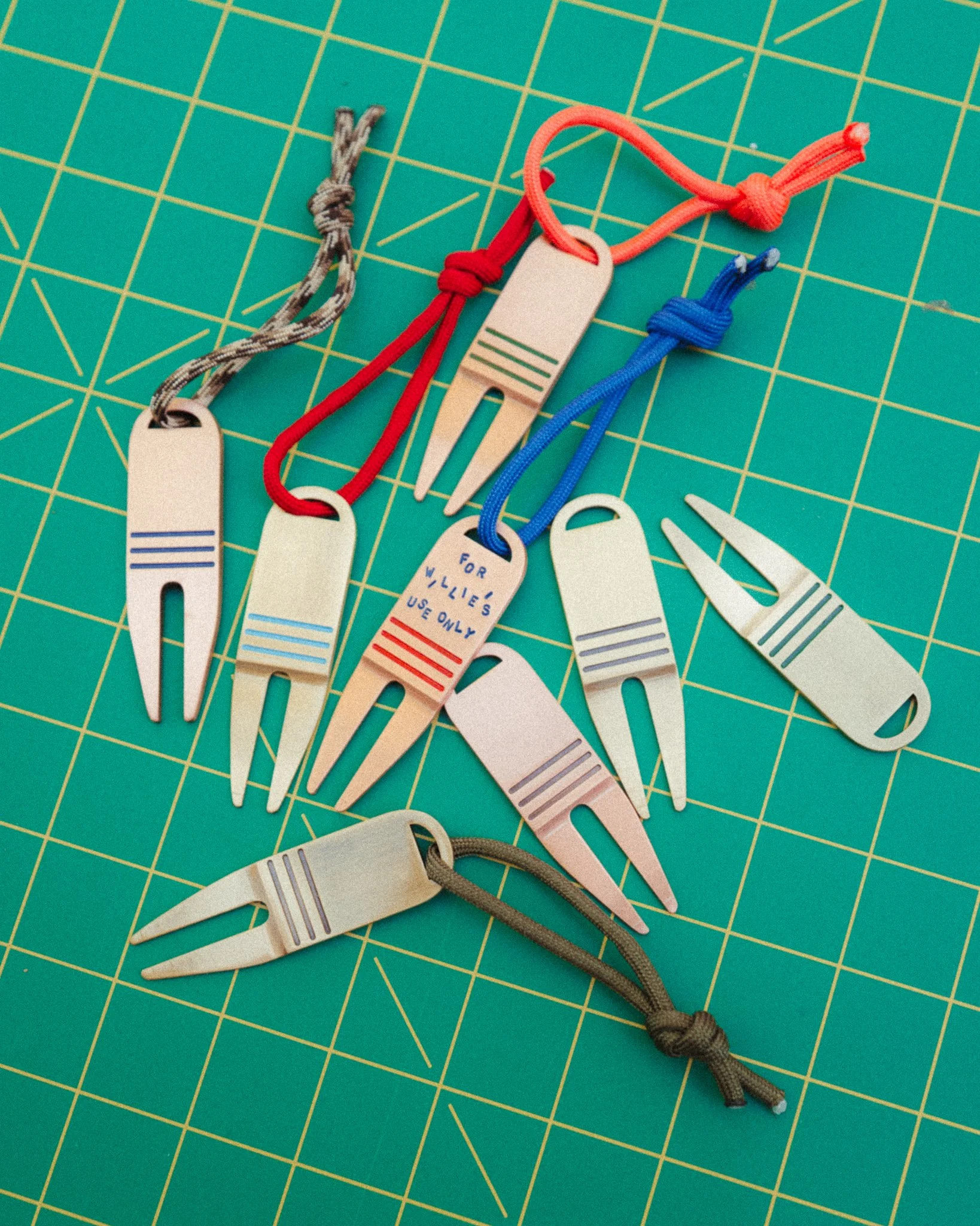 A person holding a small metallic medical tool with a flat, rounded end, outside during daytime with a background of trees and blue sky.