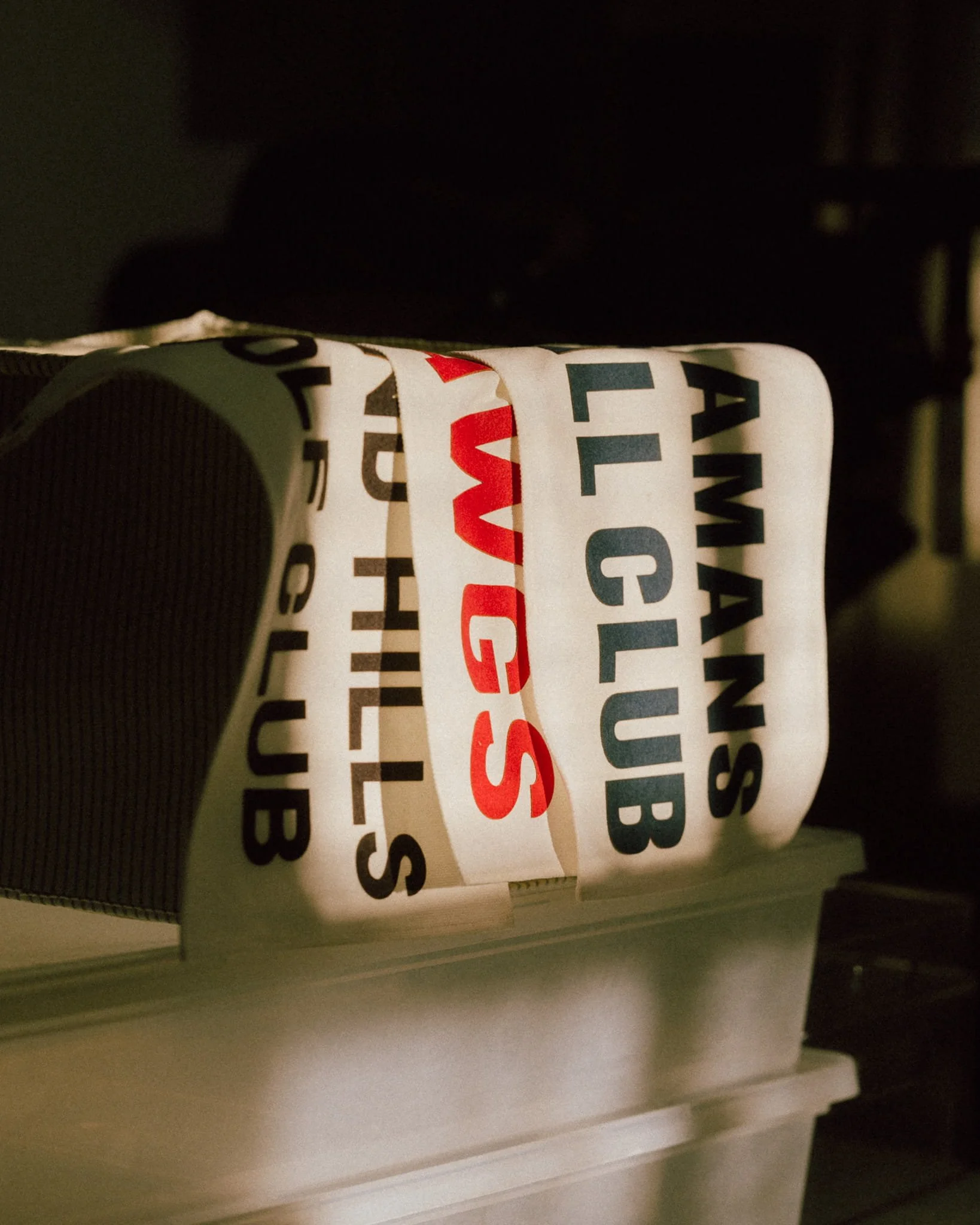 Close-up of airport baggage claim tag with the text 'AMWANS', 'CLUB', and 'WWG'S' in black and red letters.