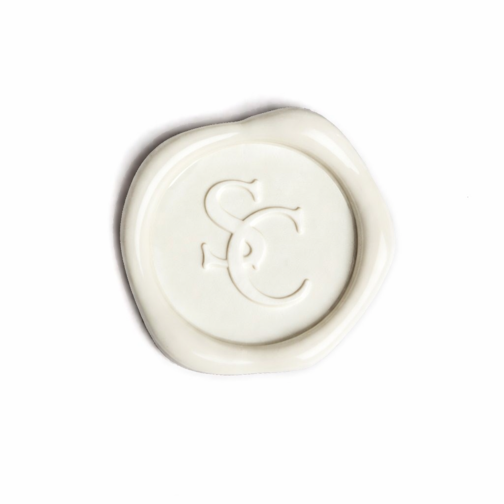 White wax seal featuring embossed intertwined initials 'S' and 'C' with irregular, waxy edges.