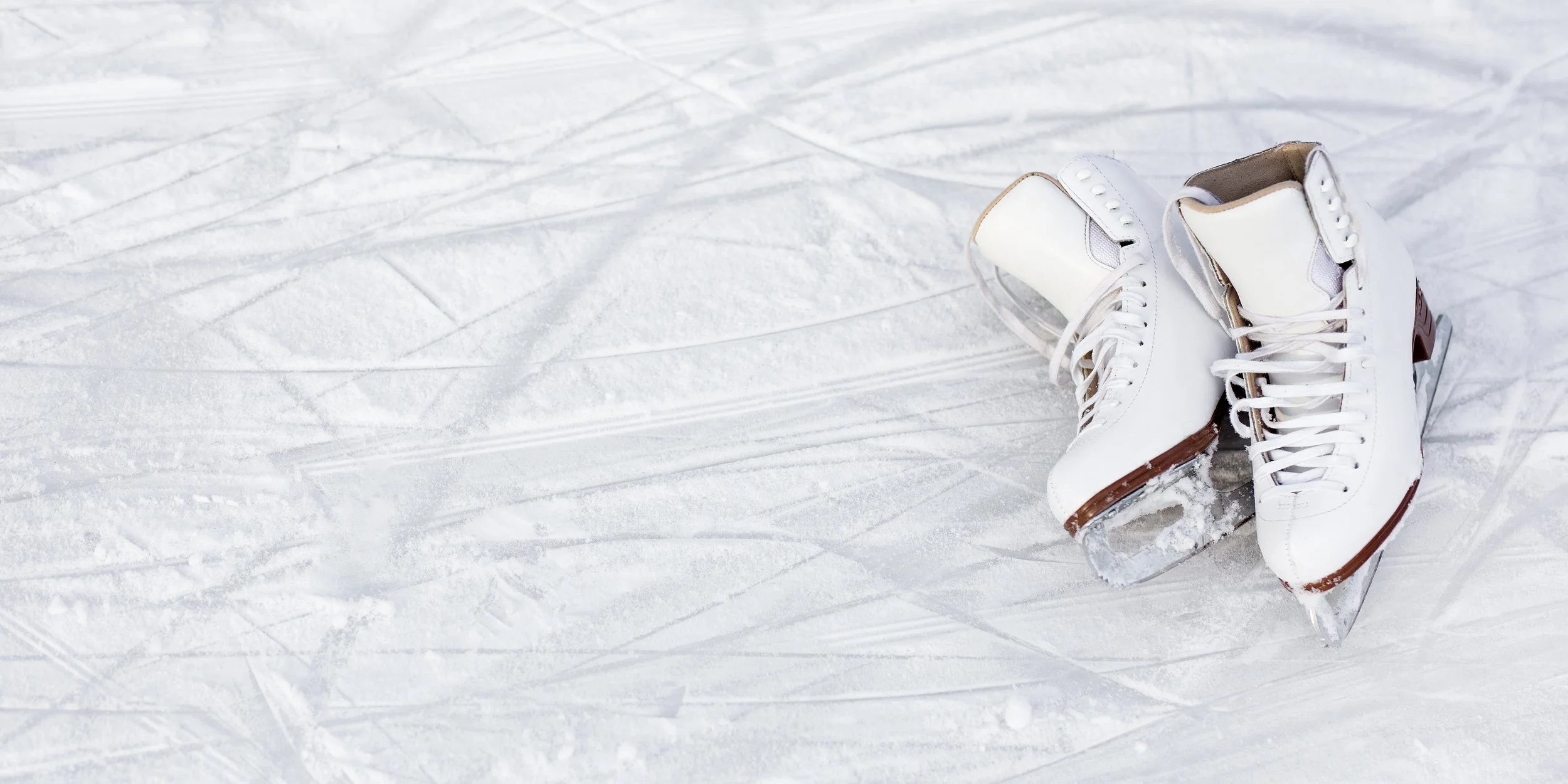 A pair of white ice skates on ice.