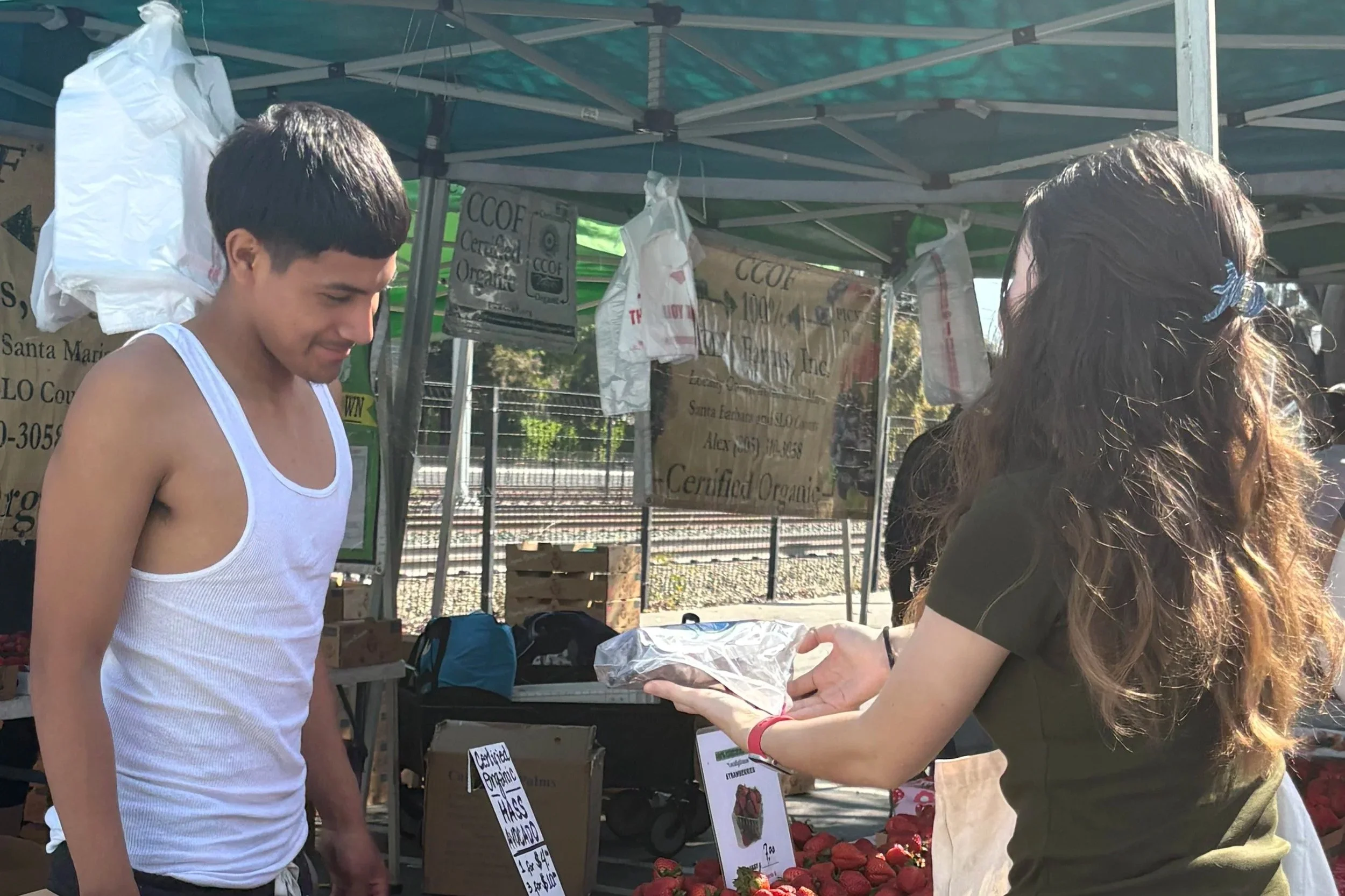 A young man in a white tank top talking to a woman with long wavy hair in a black shirt