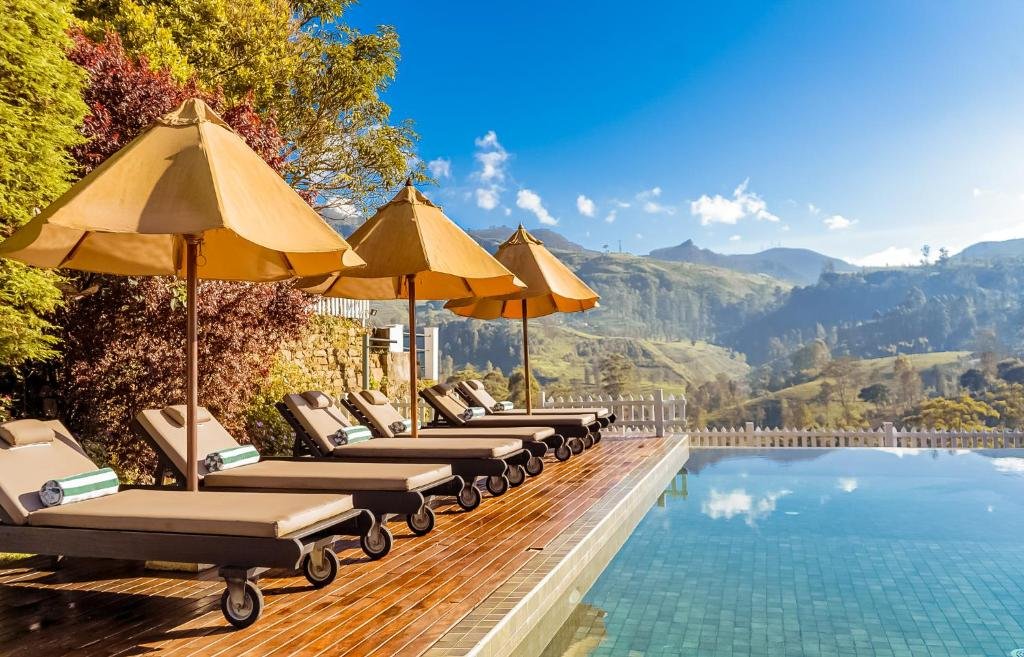 Poolside with sun loungers and umbrellas overlooking scenic mountains and greenery.