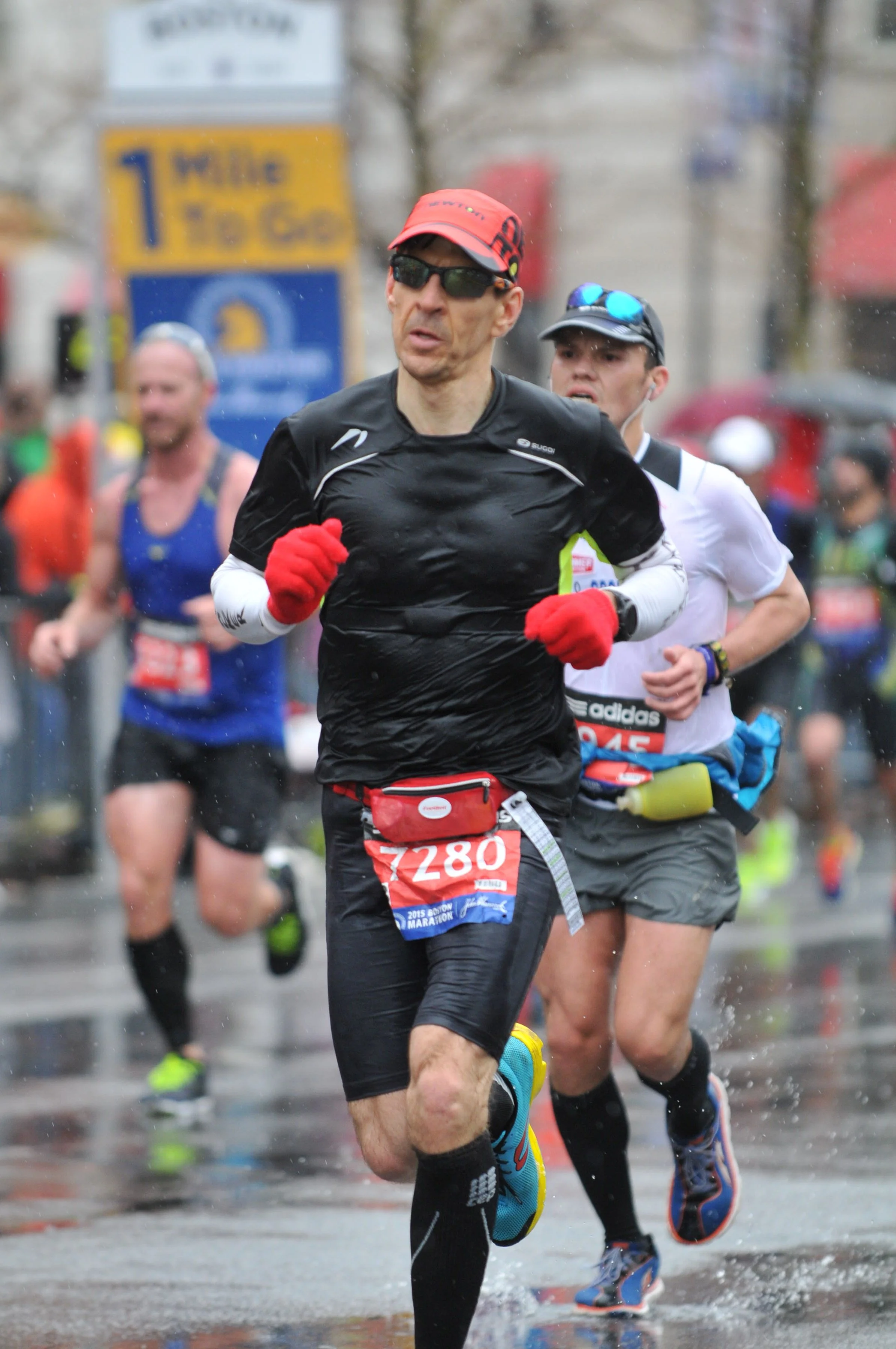 Marathon runners competing outdoors in rainy weather, wearing athletic clothing, with a race bib numbered 7280 in the foreground.