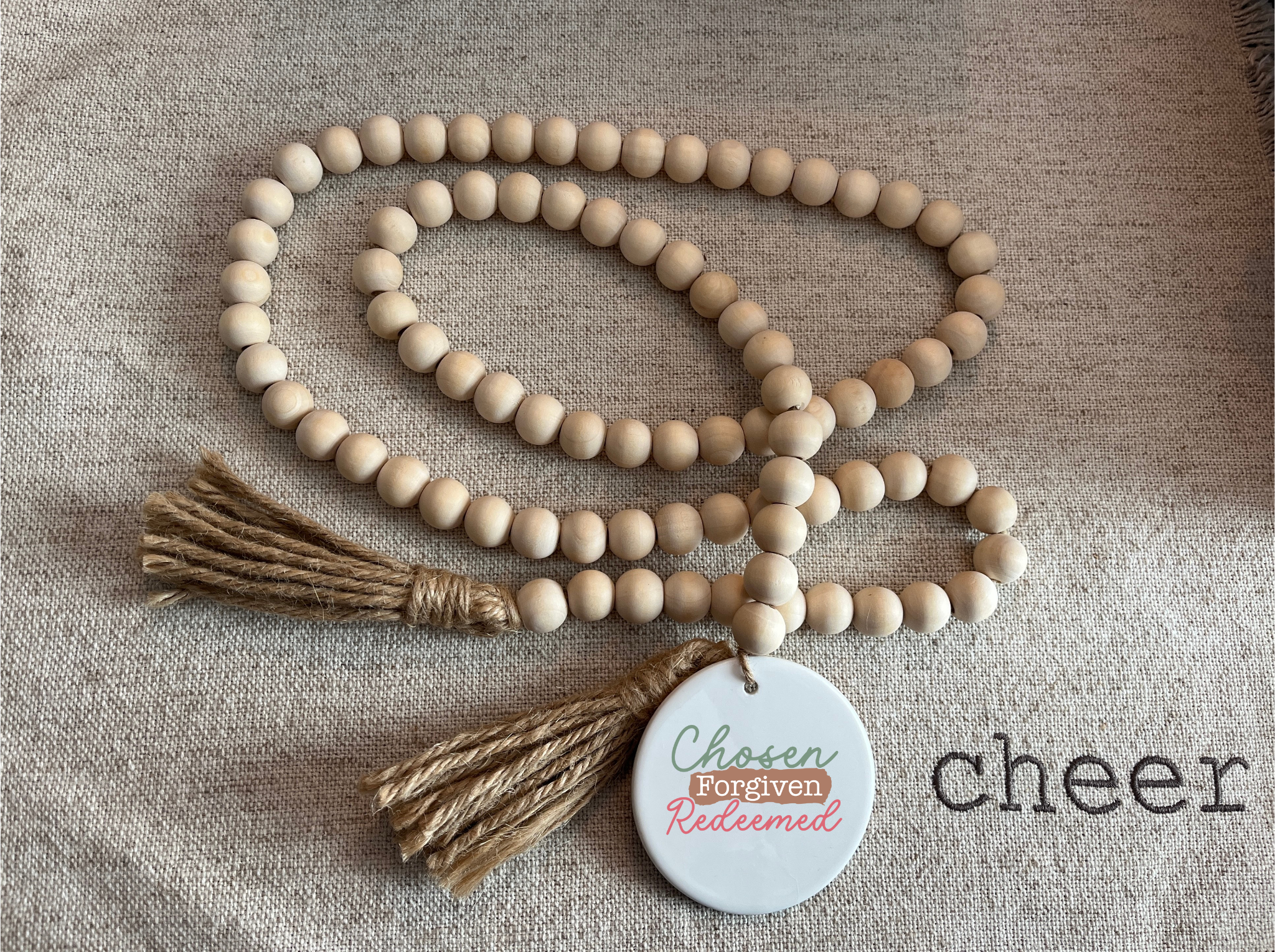 Wooden beaded necklace with tassels and a tag on a textured fabric background