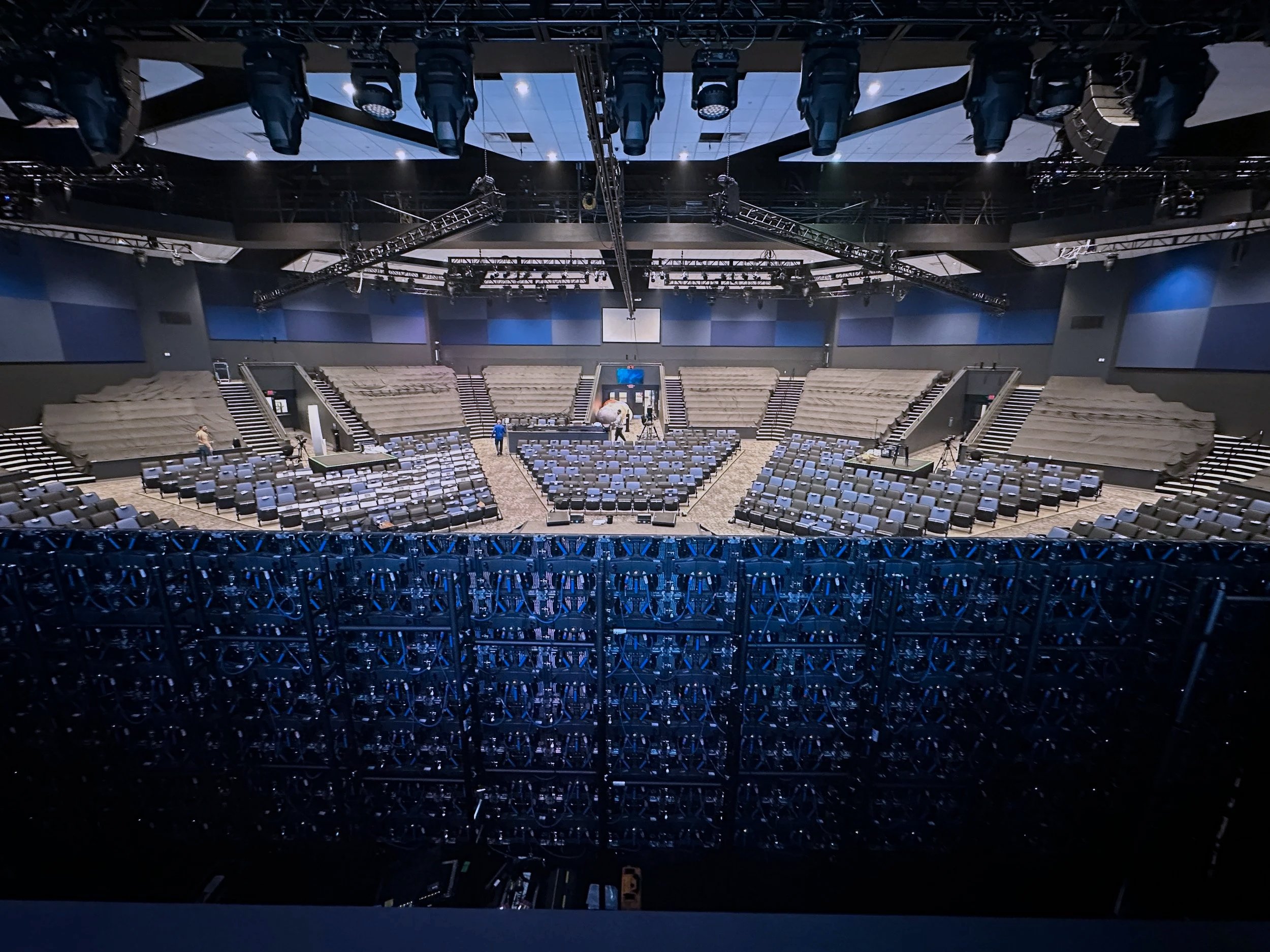 Behind a rental LED wall setup in an auditorium. Moving stage lights and truss are visible overhead.
