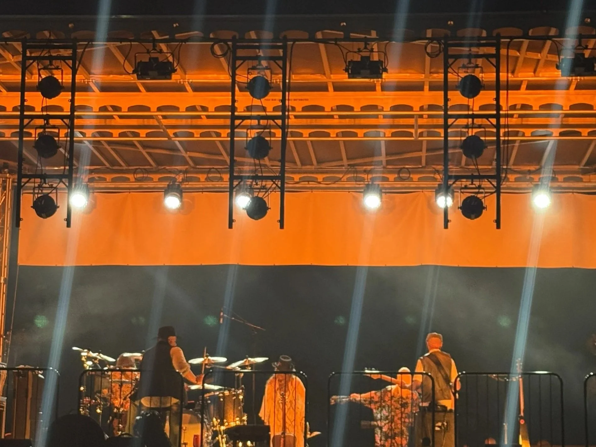 Stage with bright lights and musicians performing with drums and keyboards.